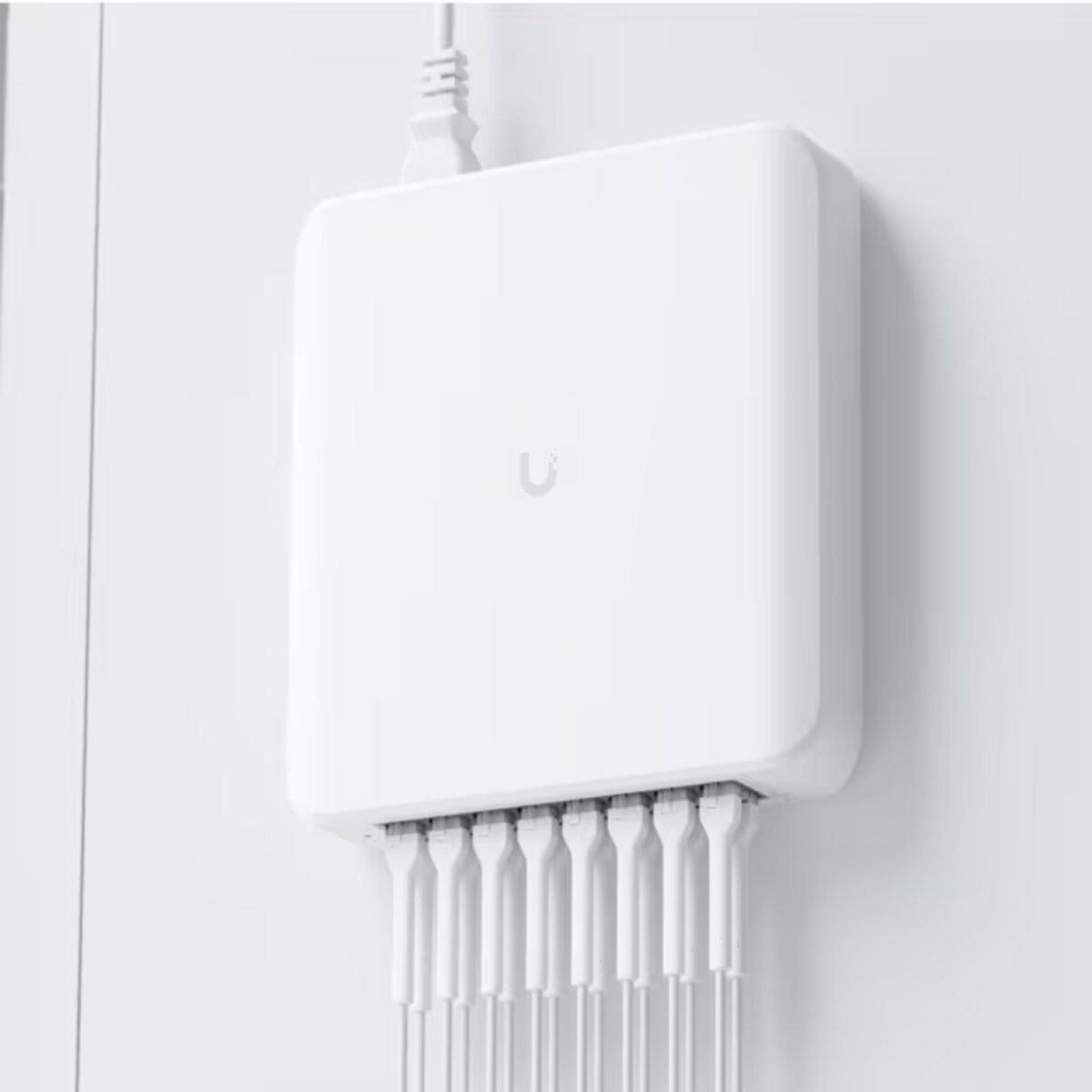 Appareil blanc sur un mur avec de multiples câbles blancs sortant du bas.