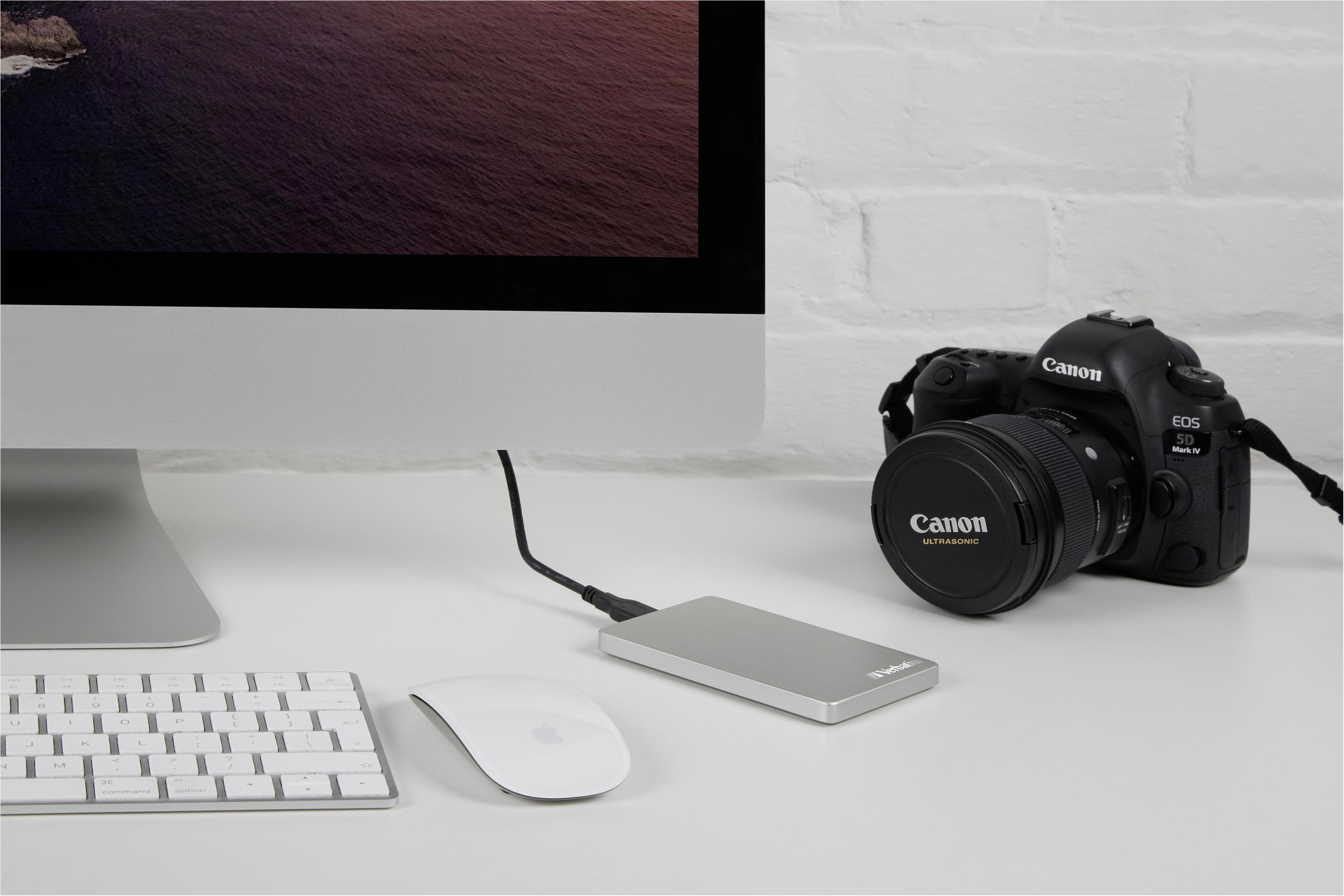 Aparat obok komputera z myszą i zewnętrznym dyskiem twardym.