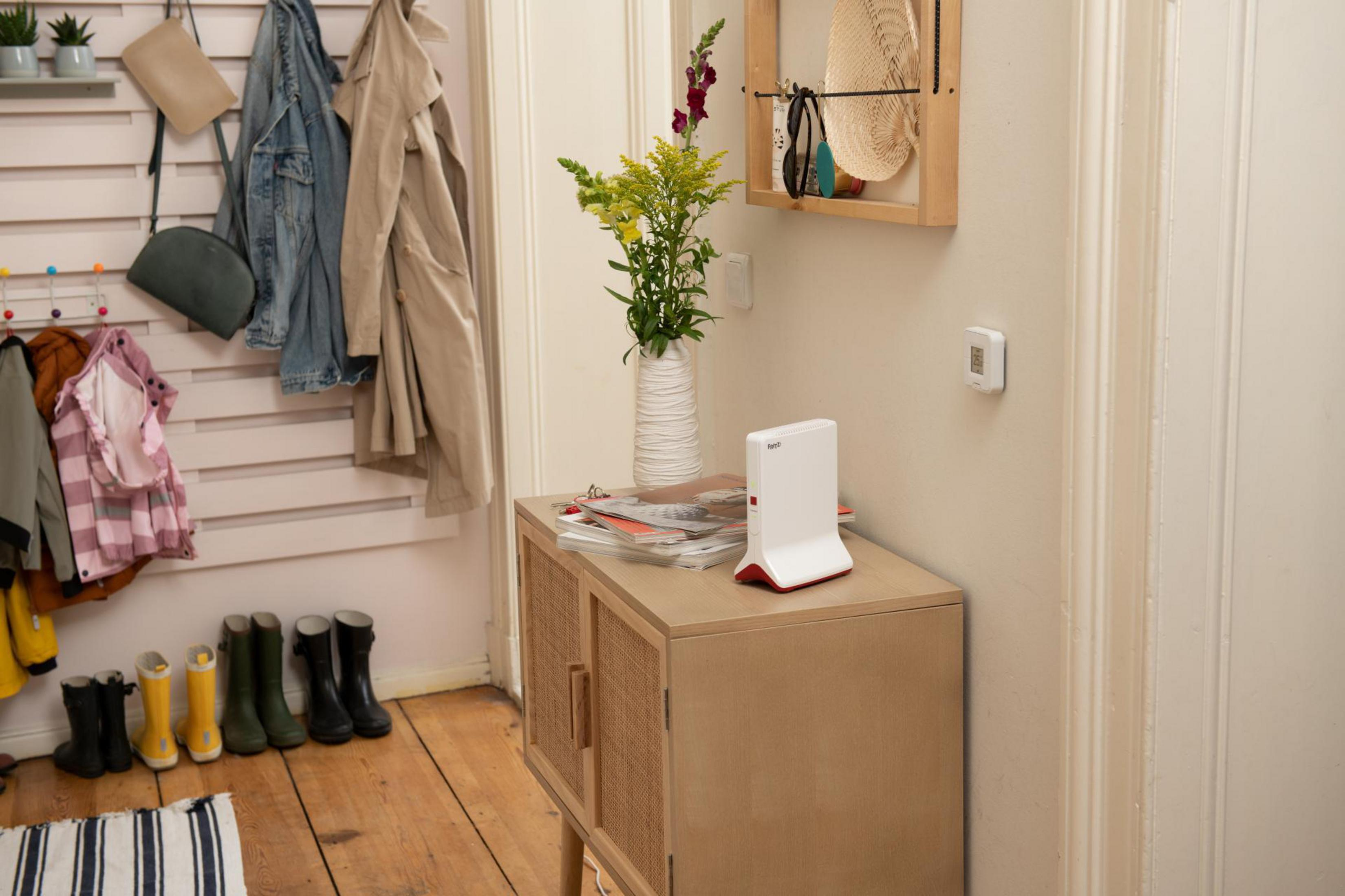 Wejście do domu. Pokazano router, kwiaty i ścienny wieszak na klucze.