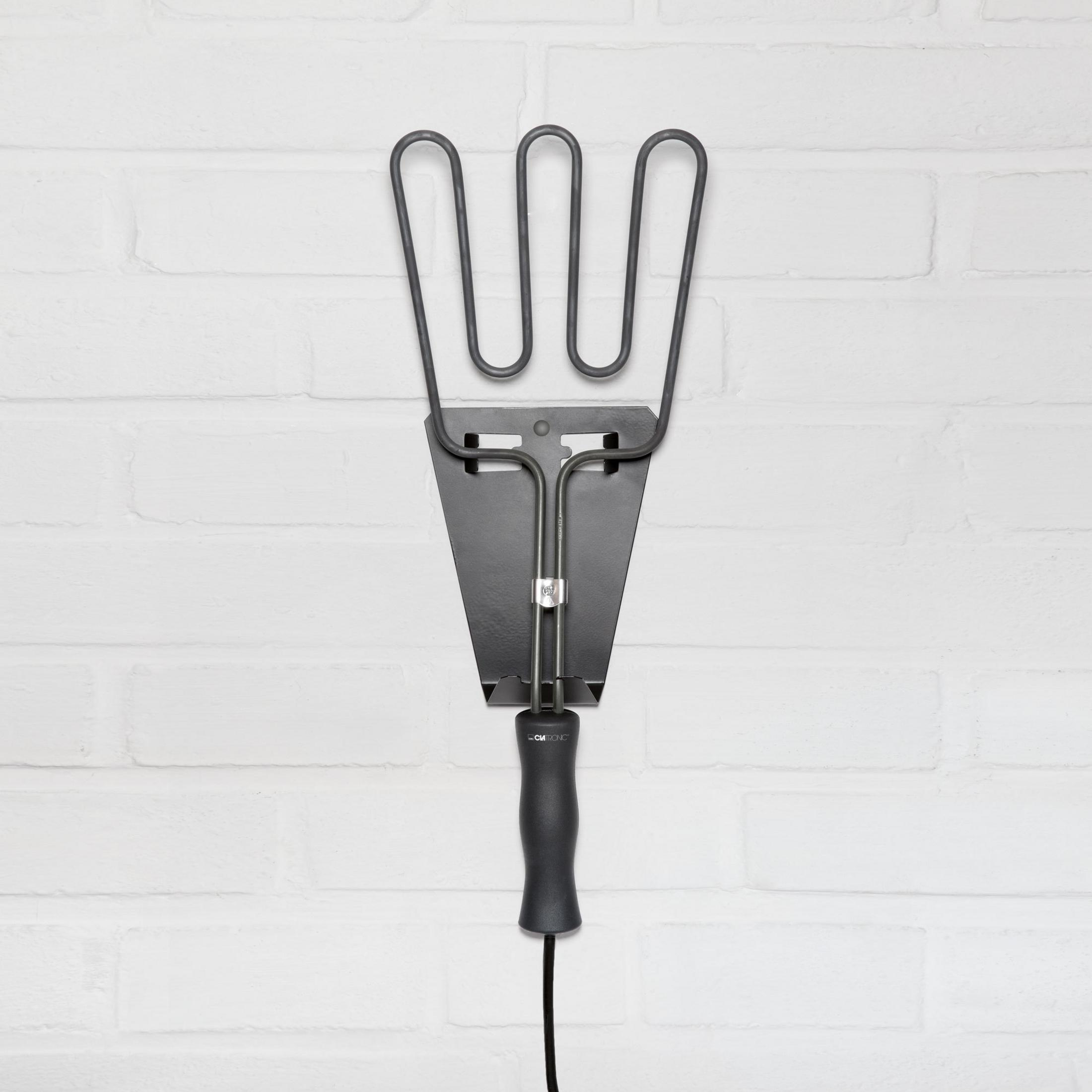 Metalowa zapalarka do węgla drzewnego zamontowana na białej ceglanej ścianie. Czarny uchwyt.