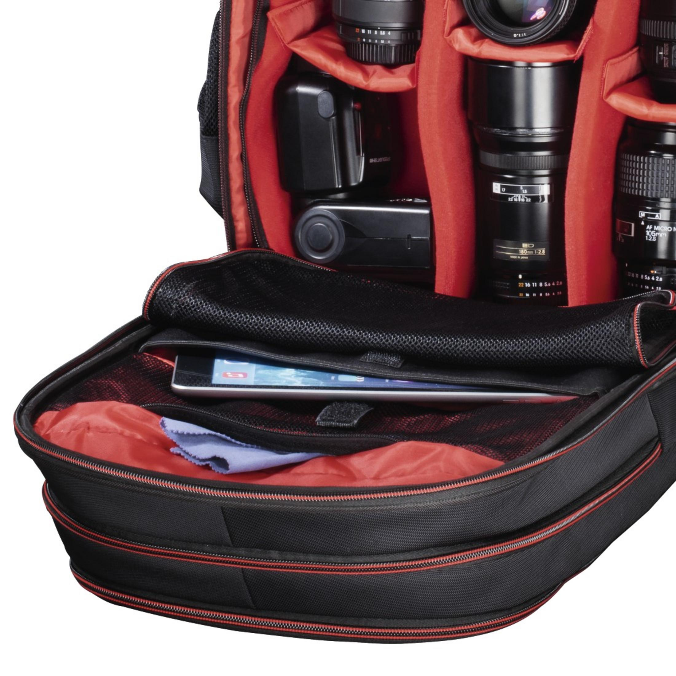 Innenraum eines schwarzen Kamera-Rucksacks mit rotem Innenfutter, mit Kameraausrüstung.