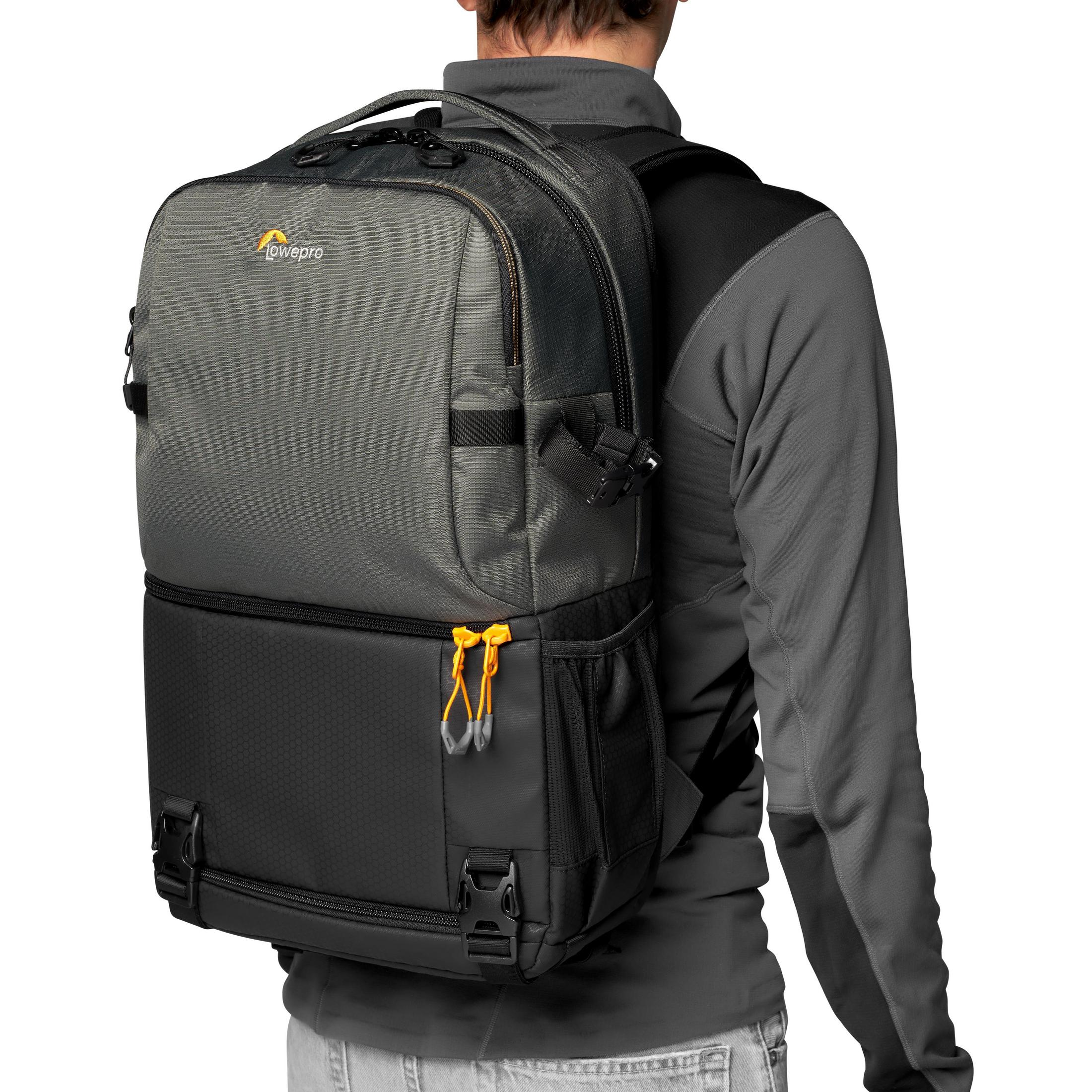Personne portant un sac à dos, gris et noir, avec des touches d'orange. Marque Lowepro.