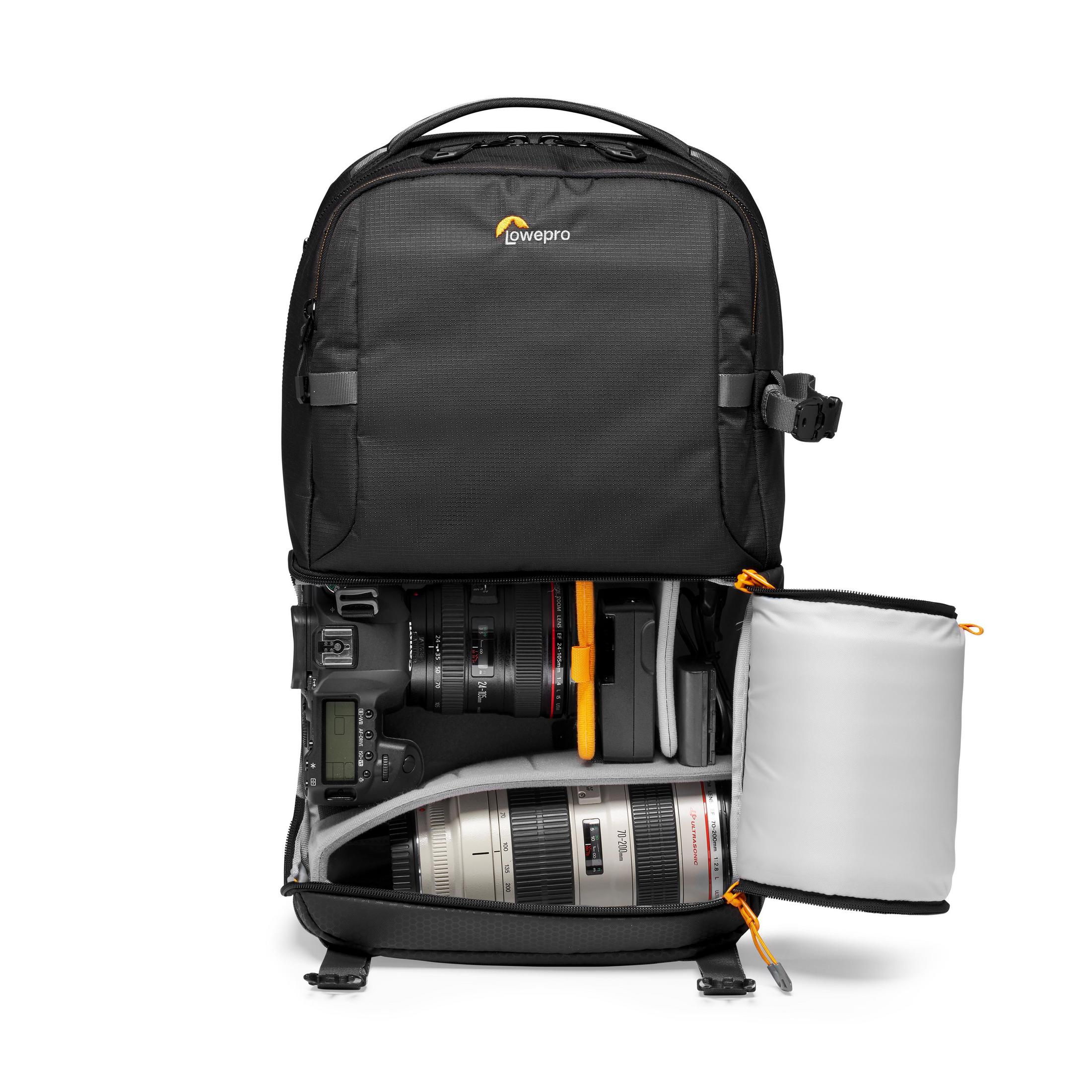 Un sac à dos noir avec un compartiment ouvert, contenant un appareil photo et des objectifs, sur fond blanc.