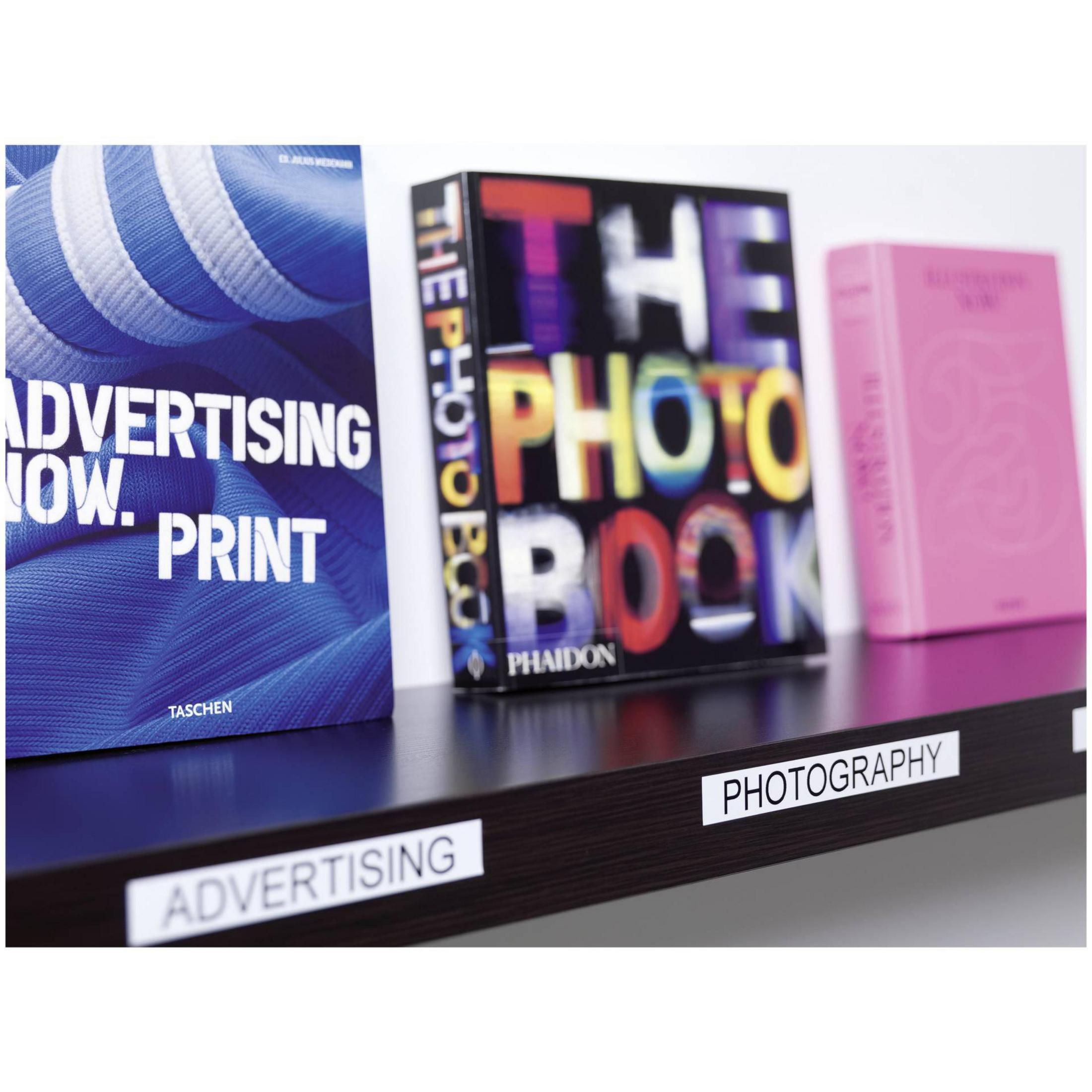 Bücher stehen in einem Regal. Die Bücher tragen Titel wie „Advertising Now. Print“ und „The Photo Book“.