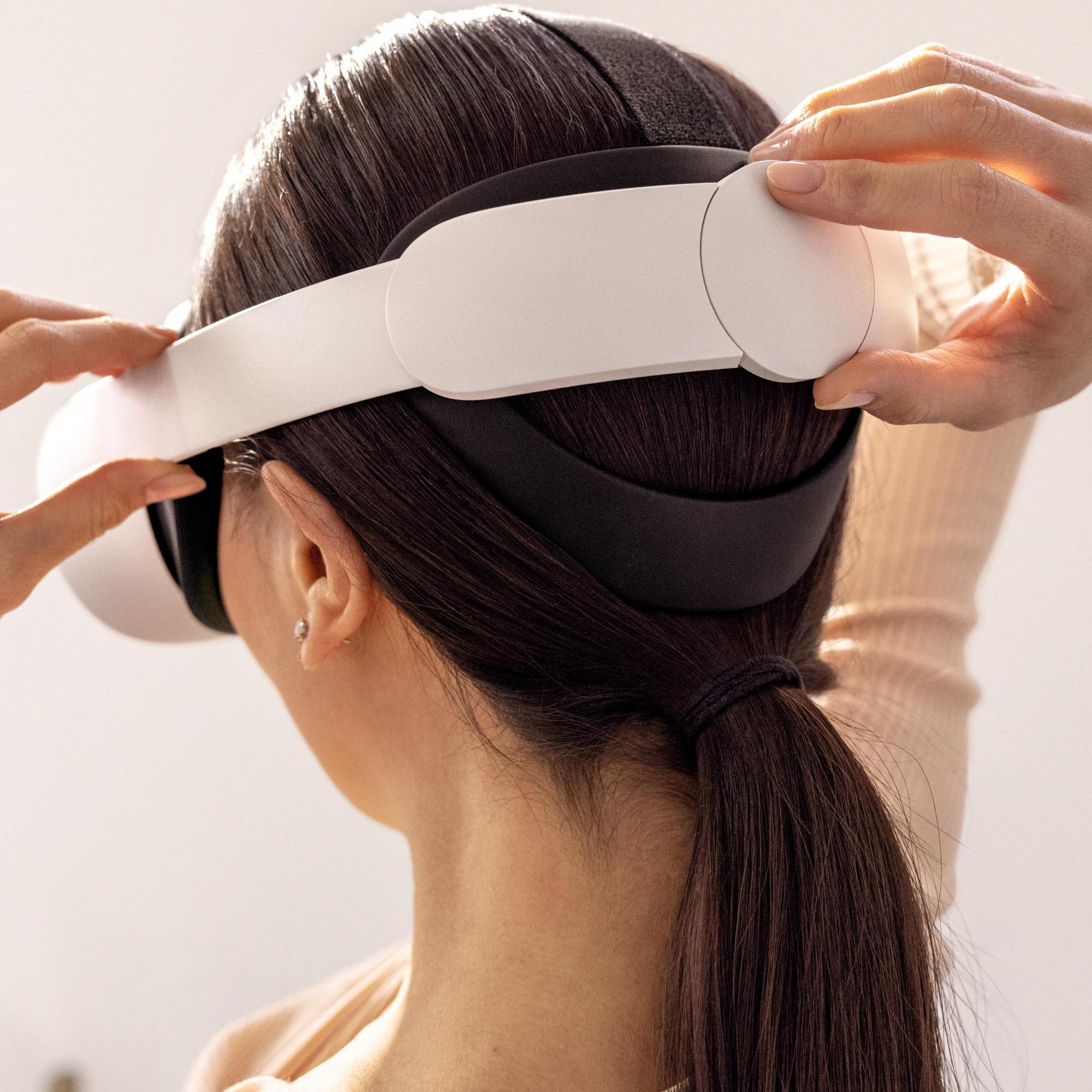 Una mujer con un casco de realidad virtual, manos ajustando las correas.