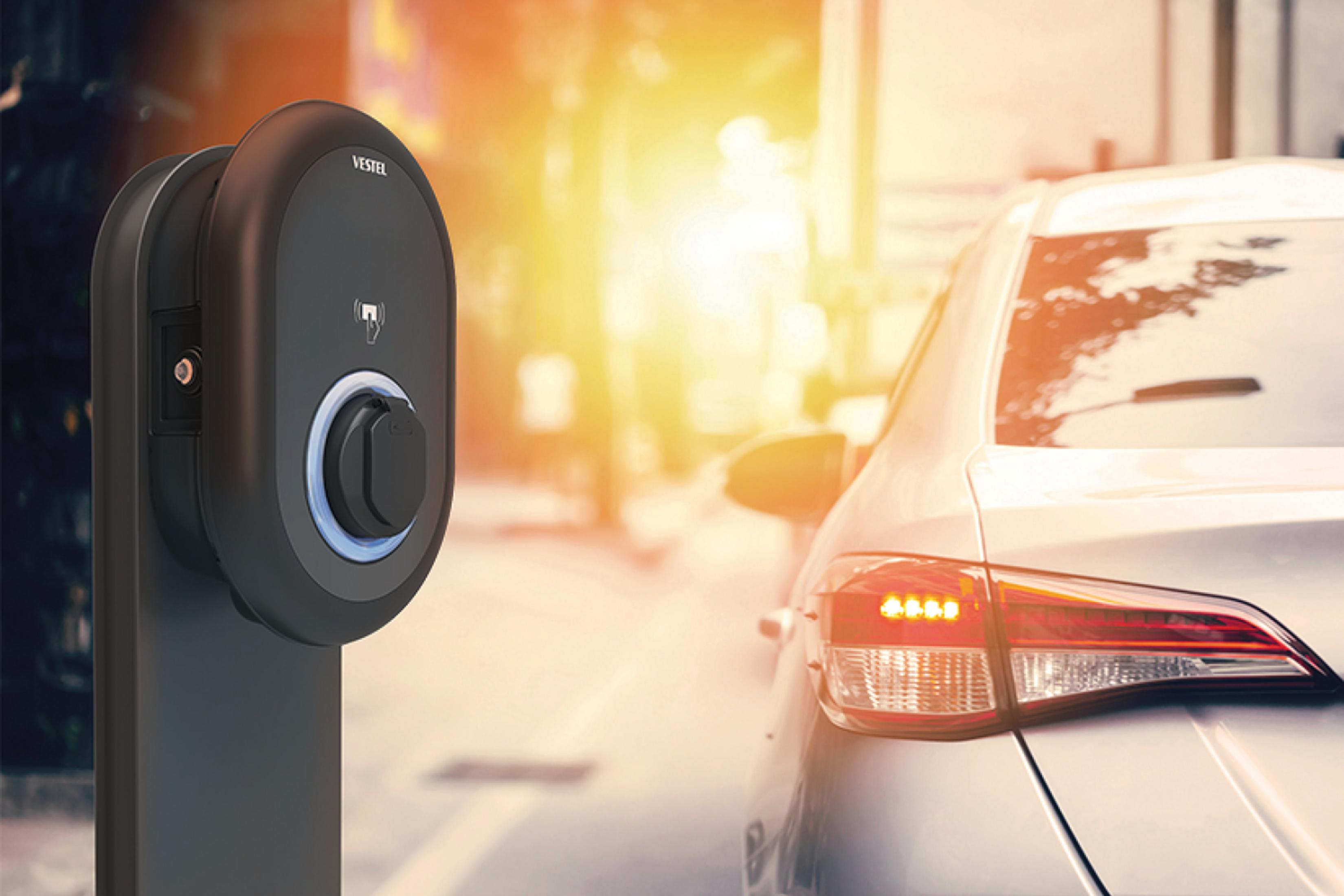 Elektroauto-Ladestation. Schwarz-graues Design. Auto im Hintergrund. Helles Sonnenlicht.