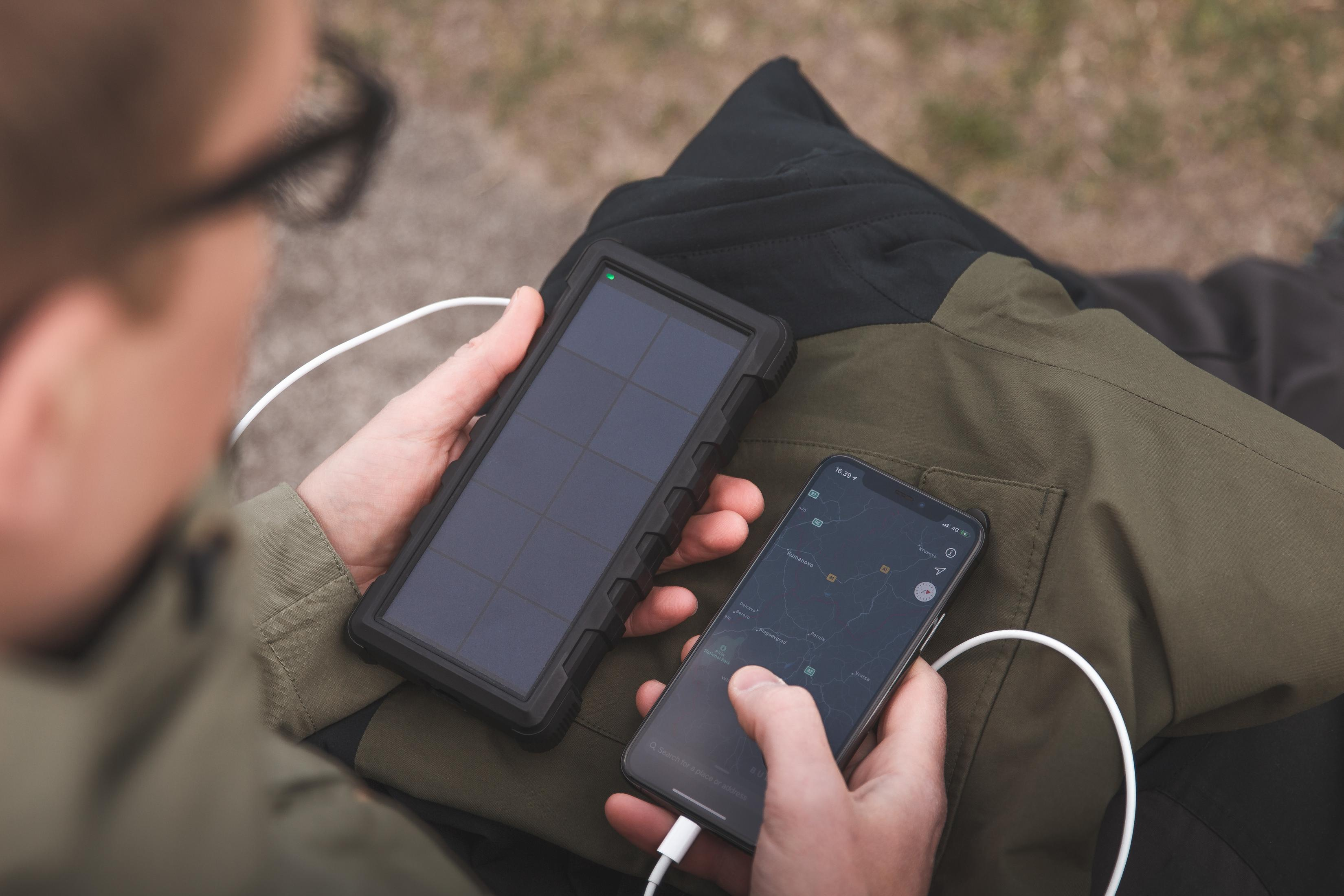 Una persona usa un caricatore solare e uno smartphone all'aperto.