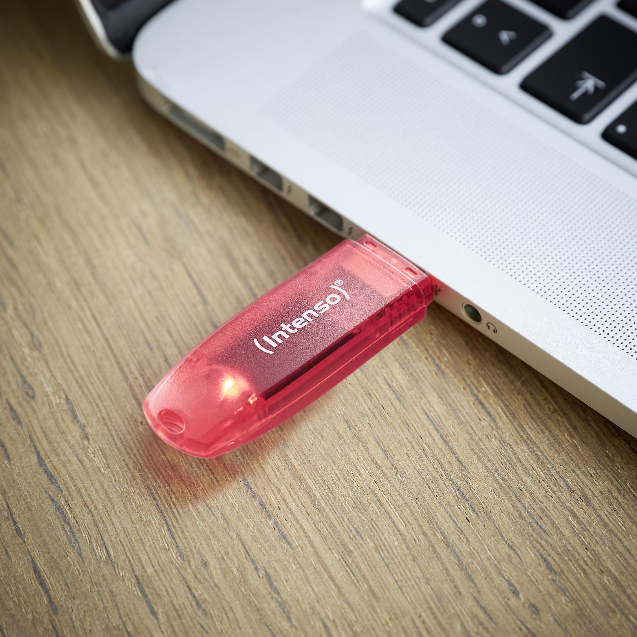 Ein roter USB-Stick an einem Laptop auf einer Holzoberfläche.