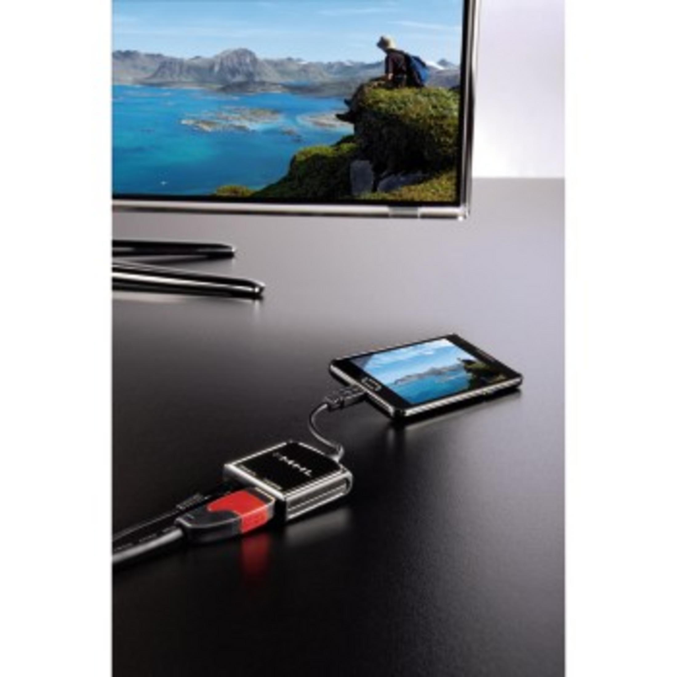 Teléfono conectado a un televisor por cable. Mesa negra, pantalla de TV con imagen de paisaje.