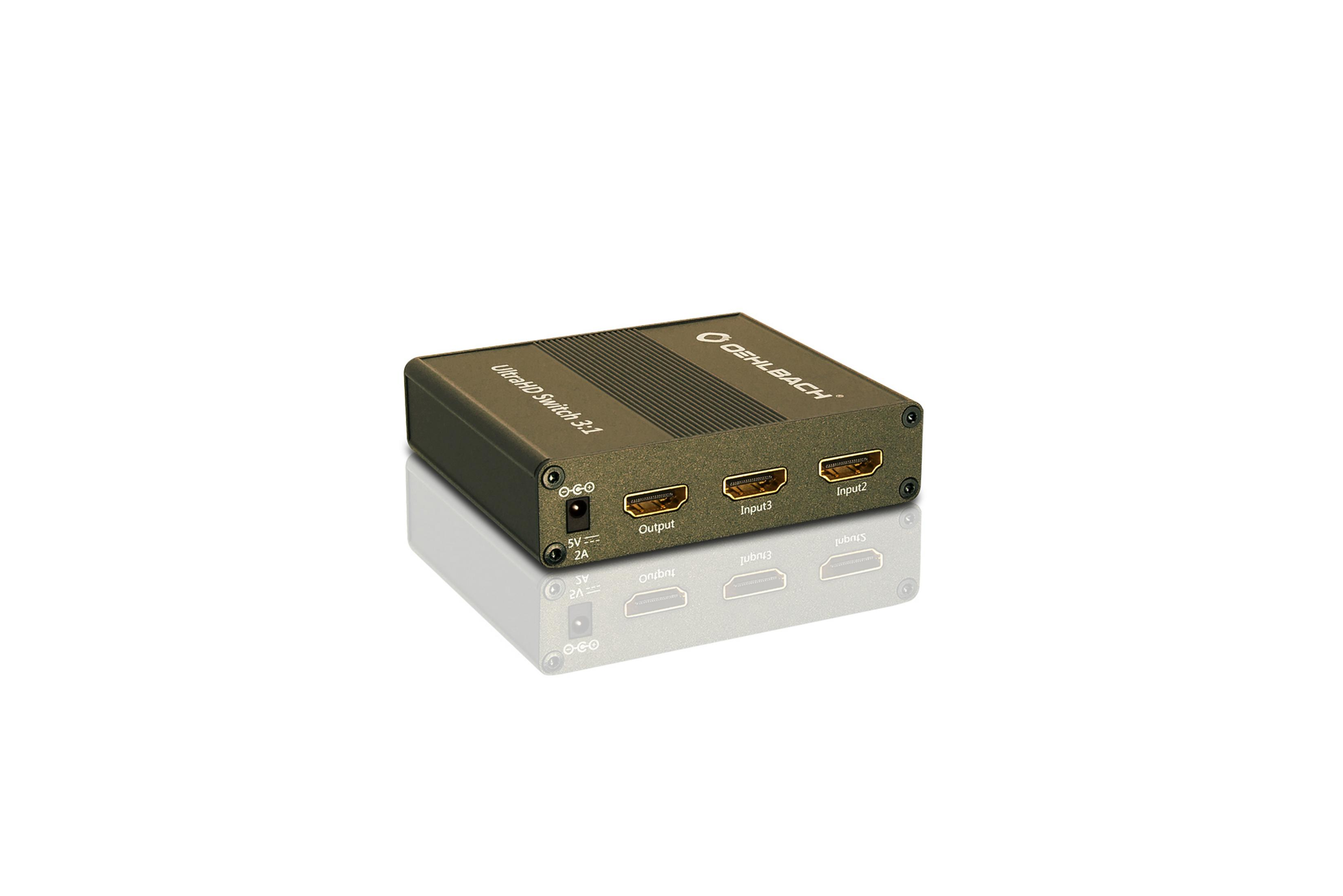 Ein schwarzer HDMI-Switch mit drei Eingangs- und einem Ausgangsanschluss, auf reflektierender Oberfläche.