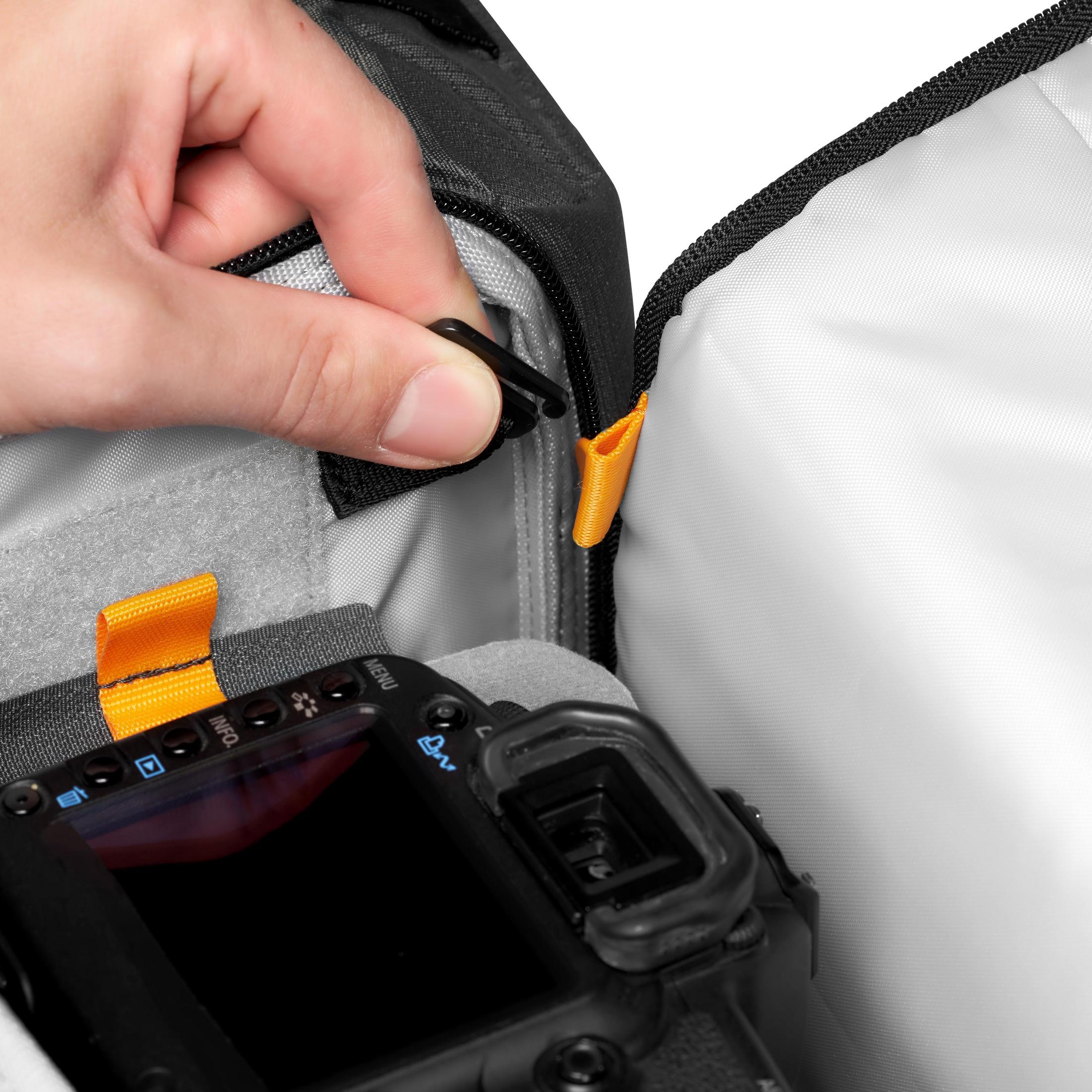 Une main ouvrant un sac photo, révélant un appareil photo.