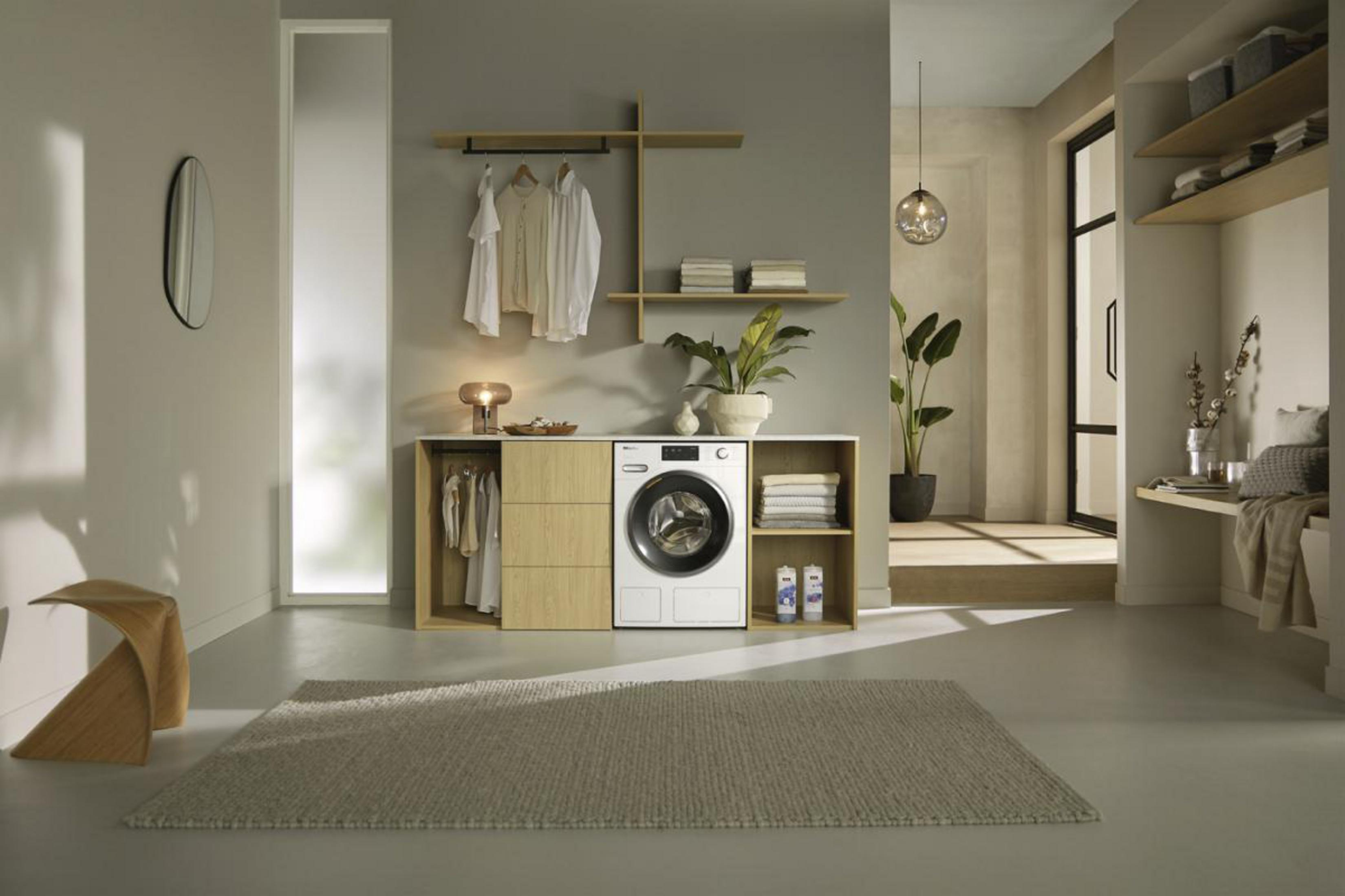 Moderne Waschküche mit Waschmaschine, Holzschränken, Kleidung, Teppich und Spiegel.