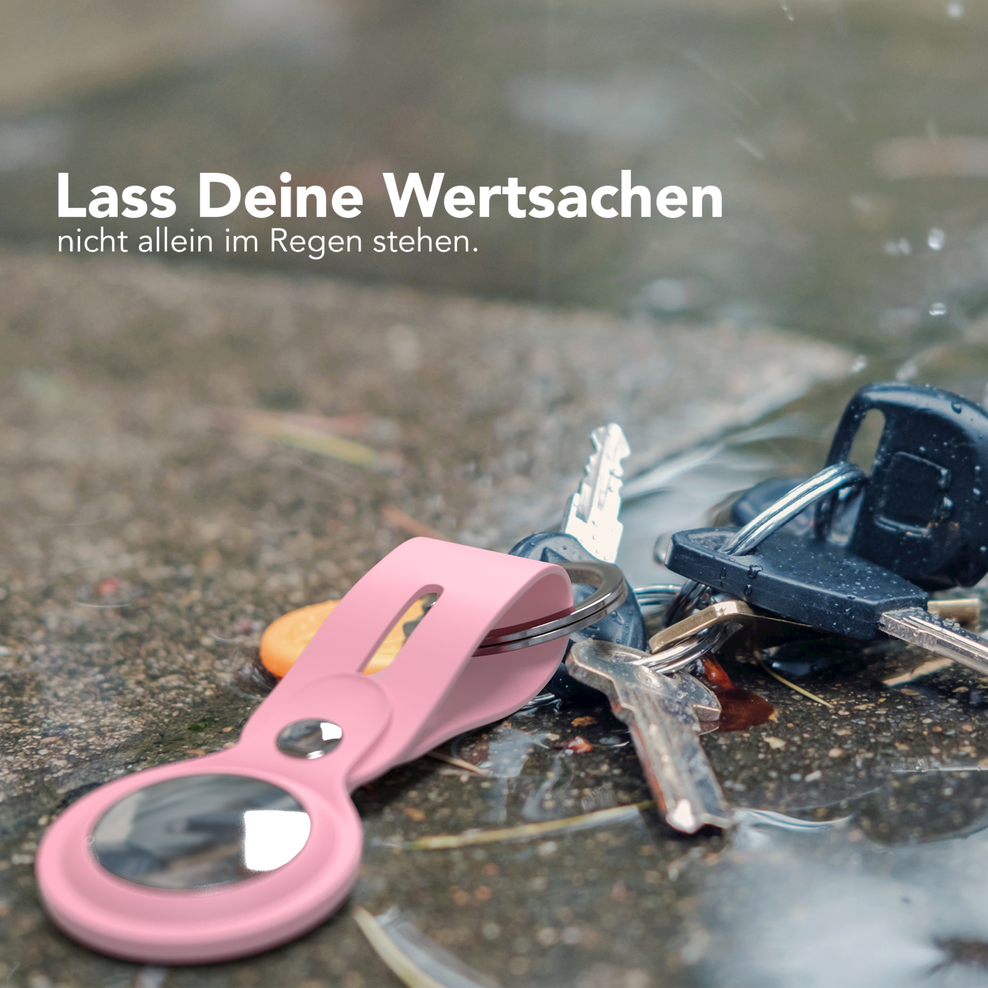 Schlüssel mit pinkfarbenem Anhänger liegen auf nassem Pflaster.