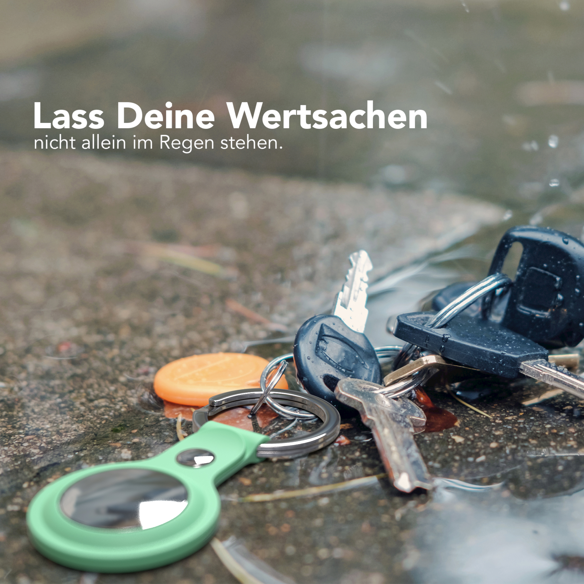 Schlüssel und ein grüner Anhänger auf nassem Untergrund.