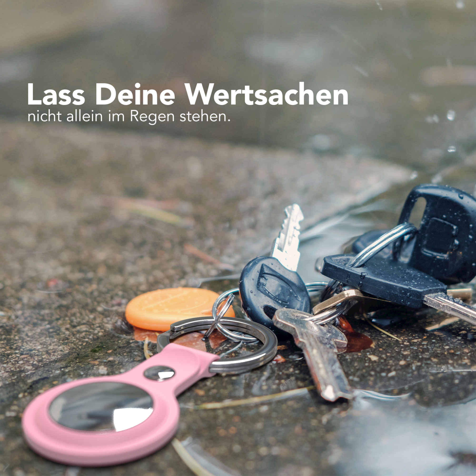 Schlüssel und ein rosa Tracker liegen auf nassem Pflaster mit dem Text: „Lass deine Wertsachen nicht im Regen stehen“.