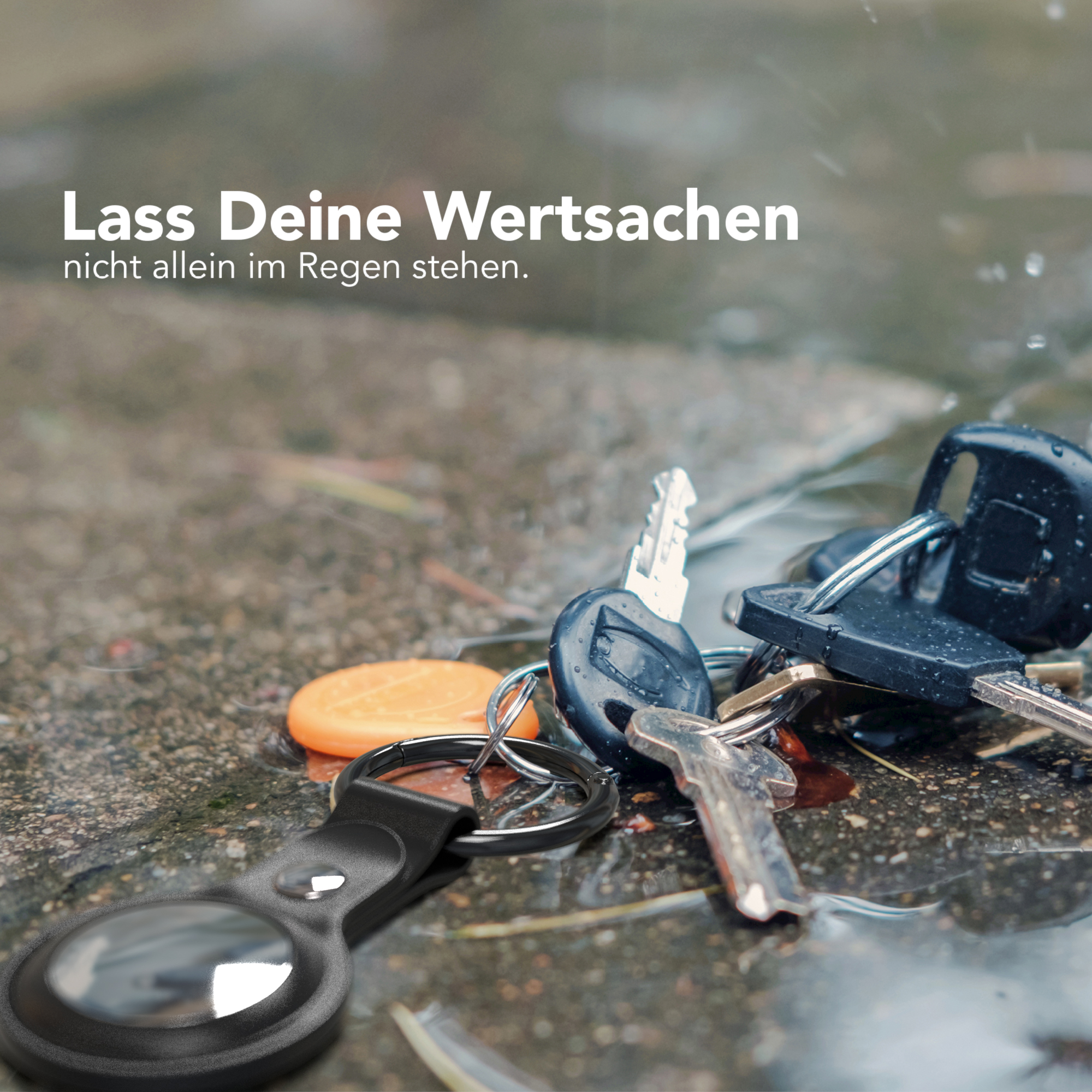 Schlüssel auf nassem Pflaster. Schwarzer Schlüsselanhänger mit rundem Anhänger, Wassertropfen.