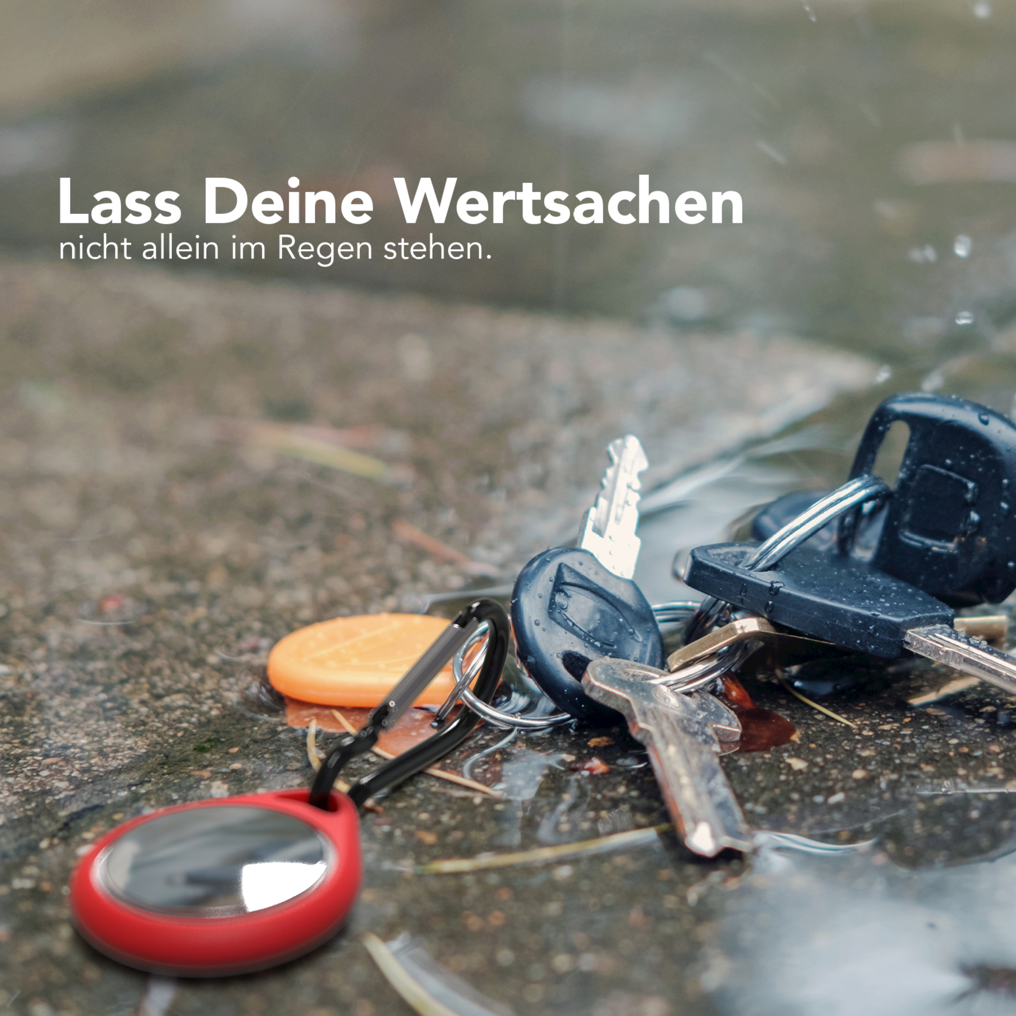 Schlüssel auf nassem Boden. Roter Schlüsselanhänger und andere Schlüssel sind sichtbar.