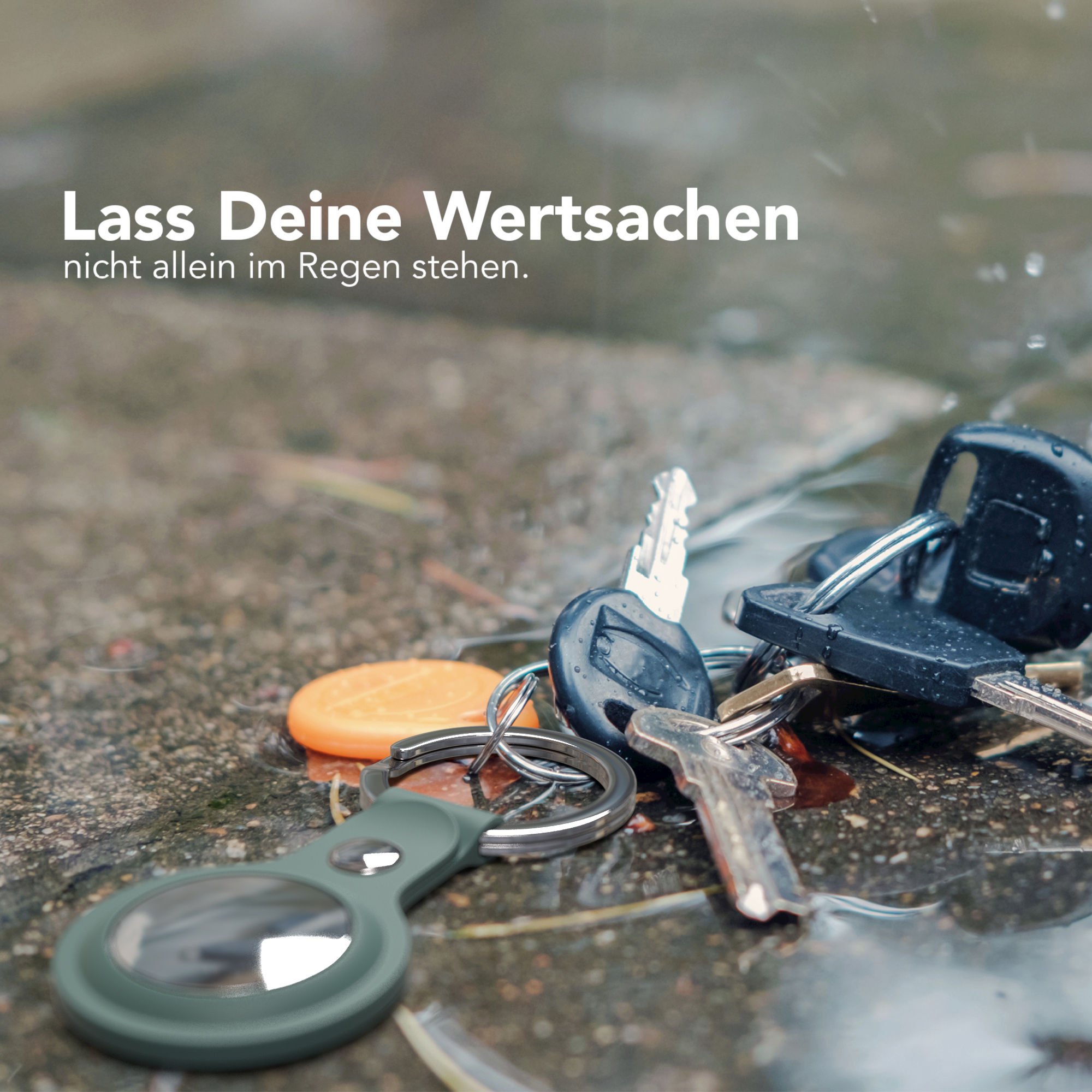 Schlüssel und ein weißer AirTag-Halter im Regen auf nassem Untergrund. Fokus liegt auf den Schlüsseln.