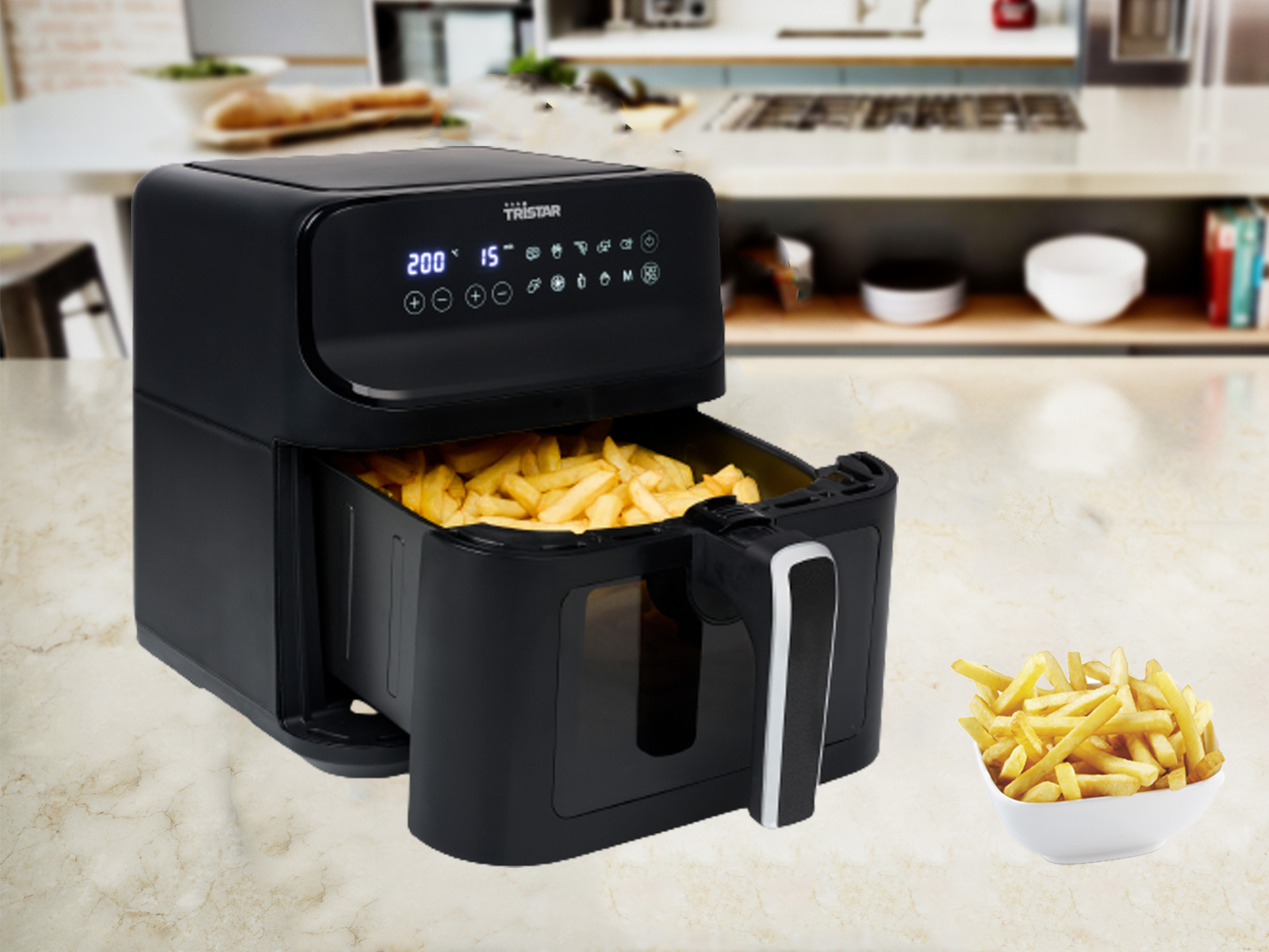 Czarna frytkownica powietrzna z frytkami w koszu i miską frytek. Tło kuchenne.