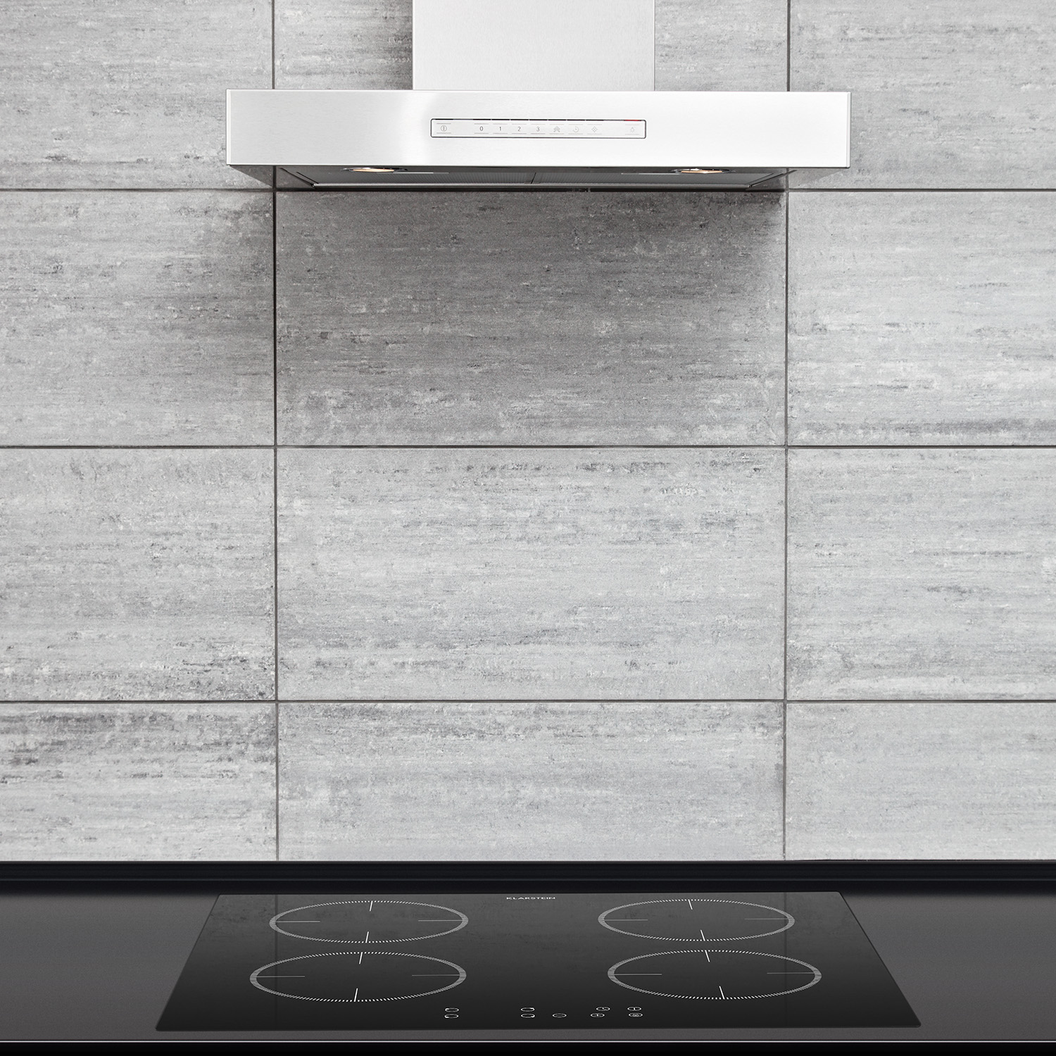 Cucina con piano cottura a induzione e cappa aspirante. Parete piastrellata grigia sullo sfondo.