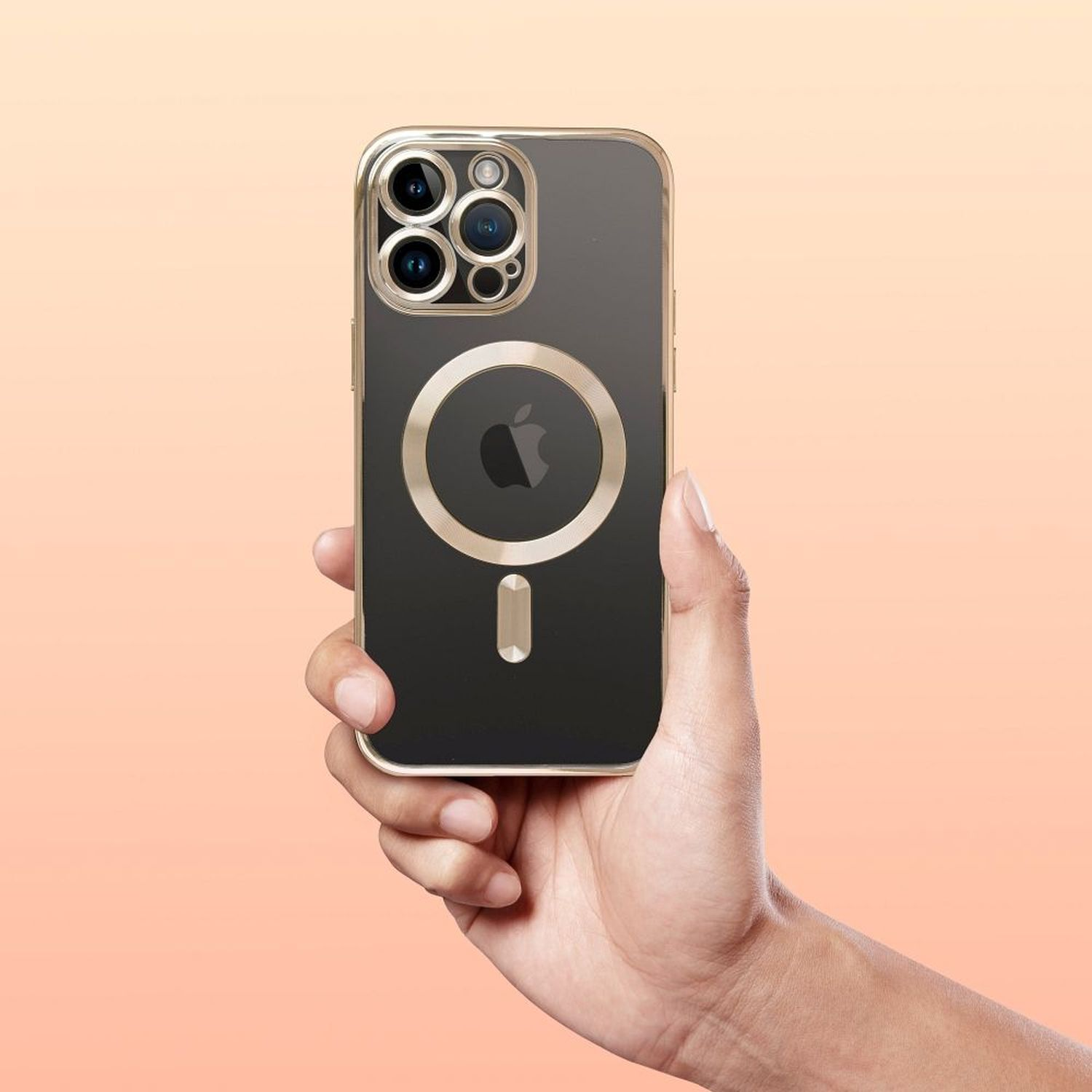 Hand, die ein schwarzes iPhone mit goldener Hülle und MagSafe-Ring hält, auf pfirsichfarbenem Hintergrund.