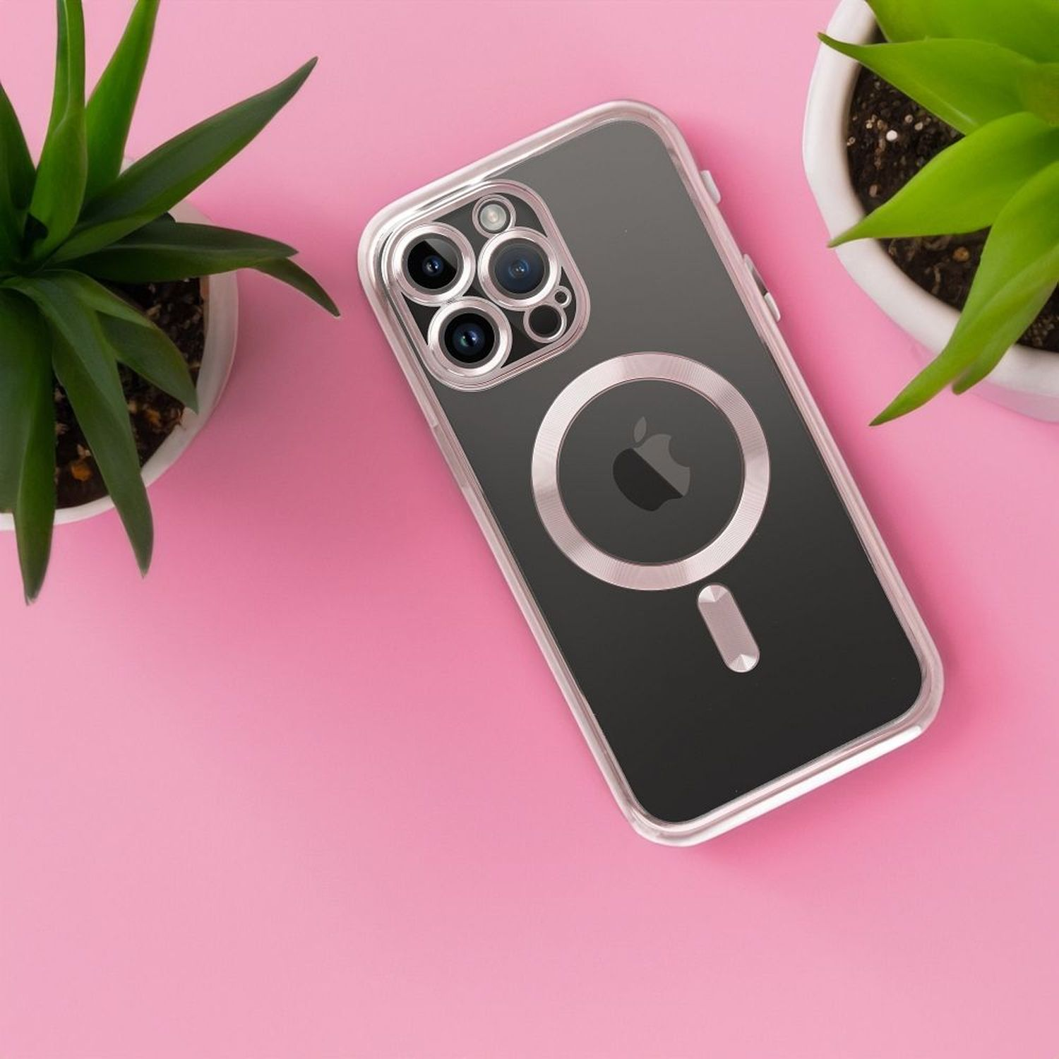 iPhone in transparentem Case mit Pflanzen auf rosa Oberfläche. Das Telefon ist rechts.