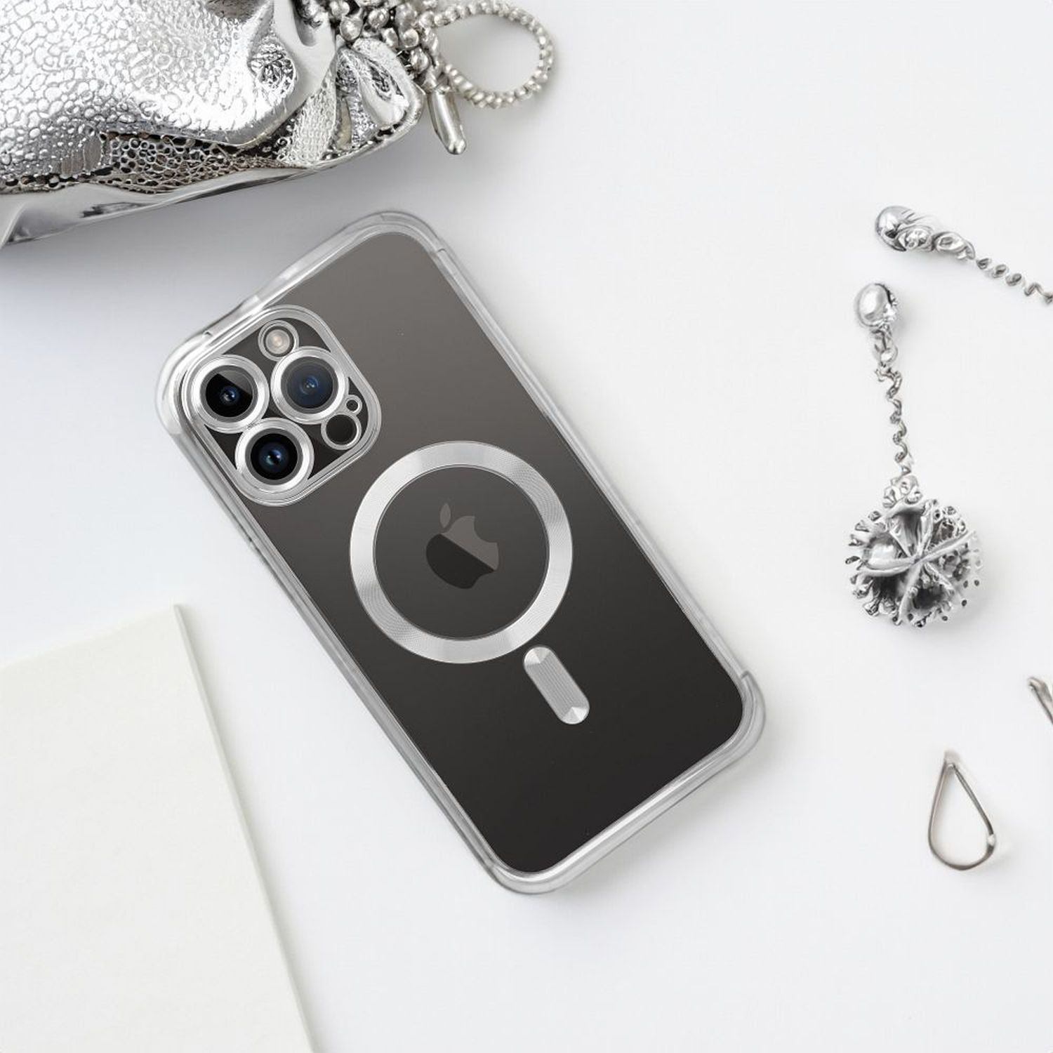 Transparente iPhone-Hülle mit MagSafe und Zubehör auf weißer Oberfläche.