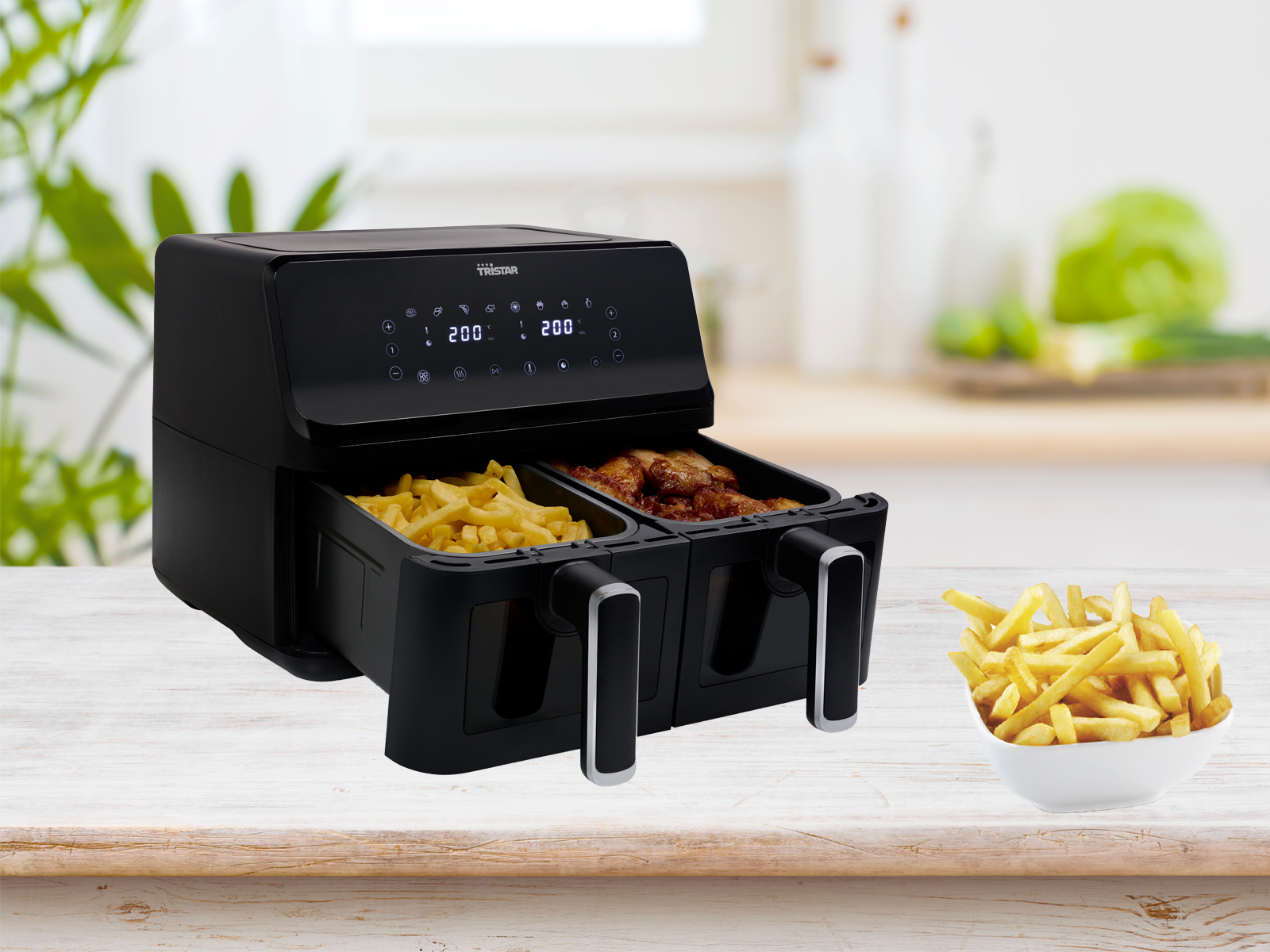 Czarna frytkownica beztłuszczowa z dwoma koszami, z jedzeniem i frytkami.
