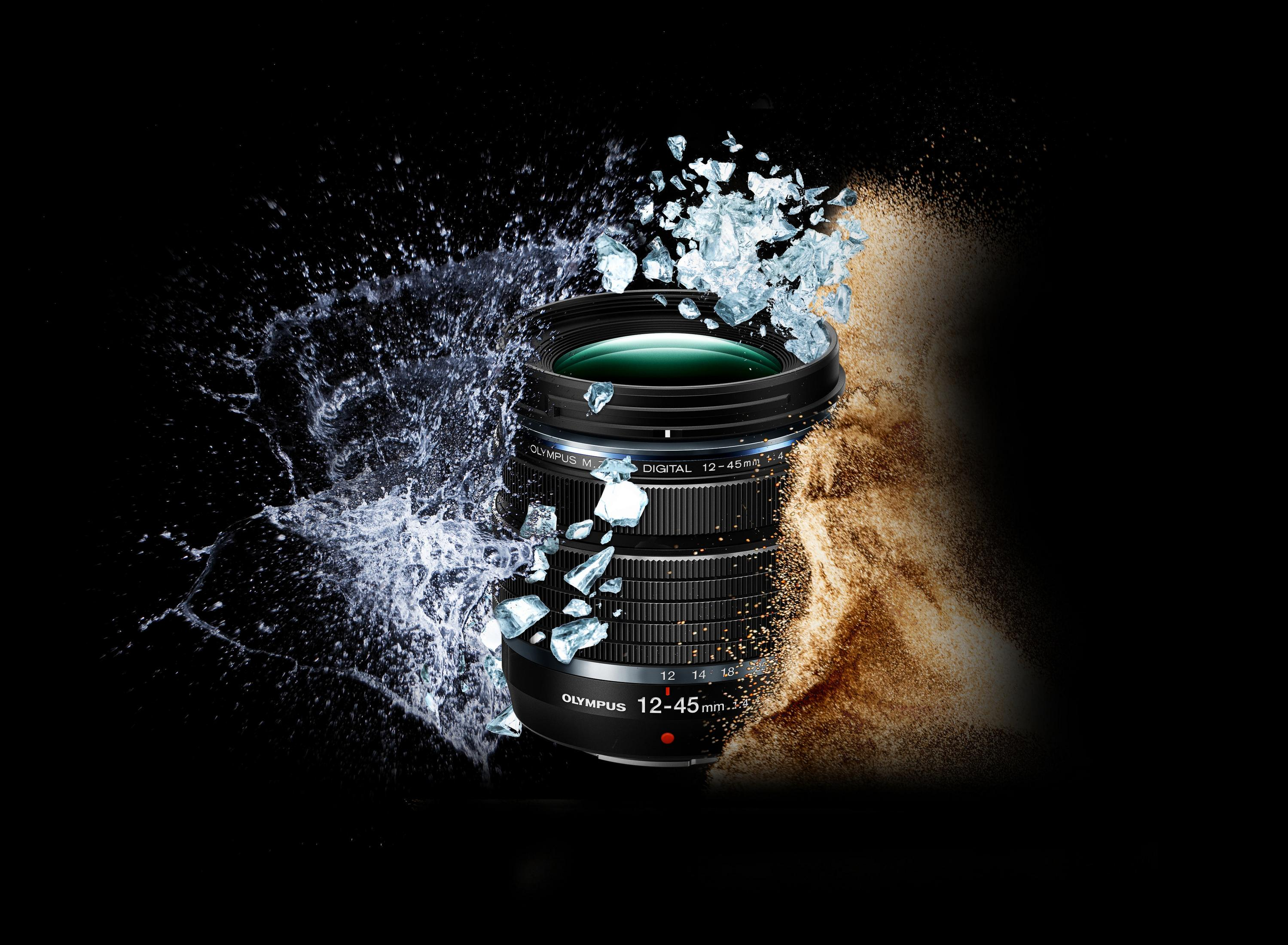 Ein Kameraobjektiv mit Wasser- und Sandeffekten. Das Objektiv ist schwarz mit Olympus-Logo.