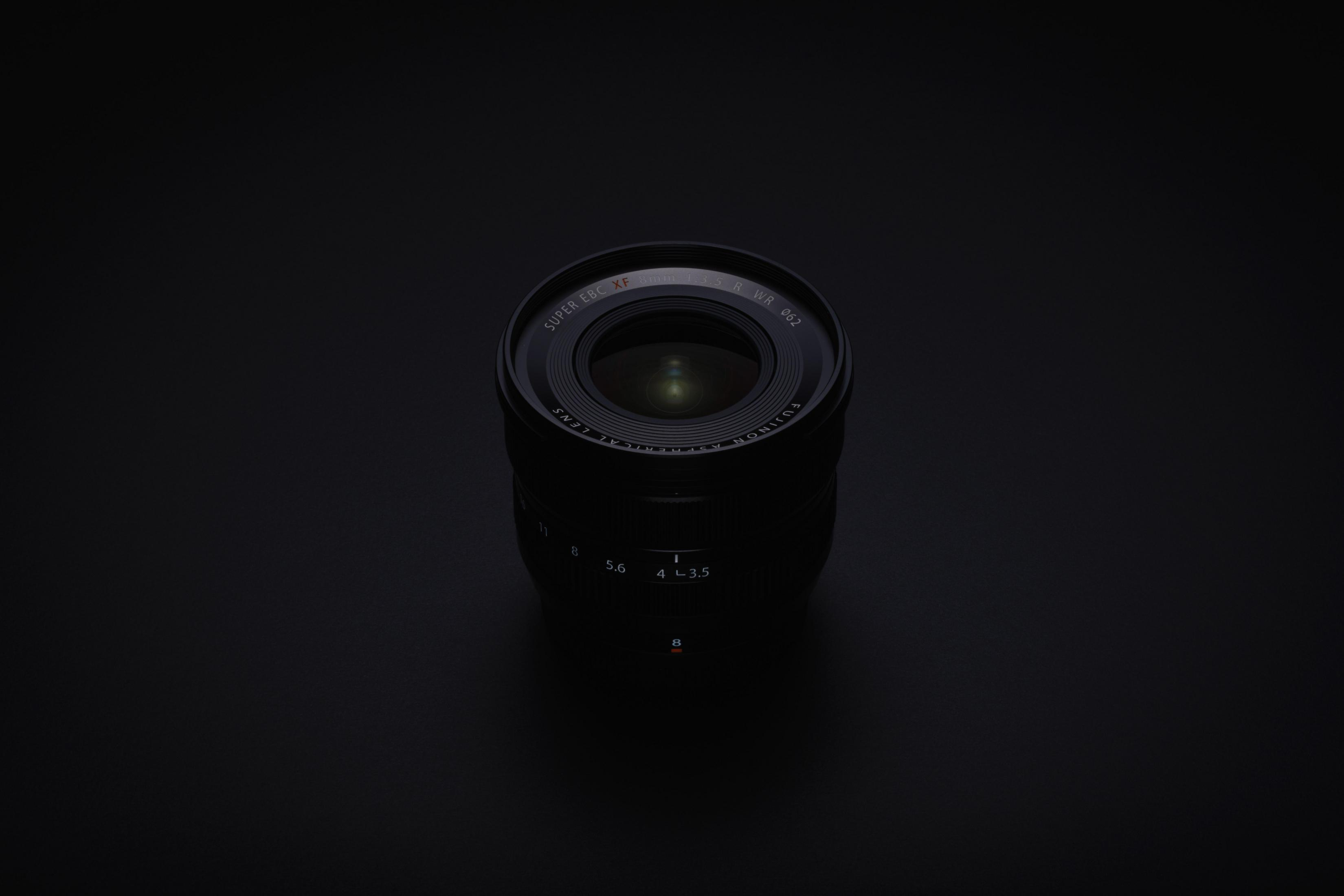 Czarny obiektyw na czarnym tle, z obiektywem skierowanym w stronę widza.