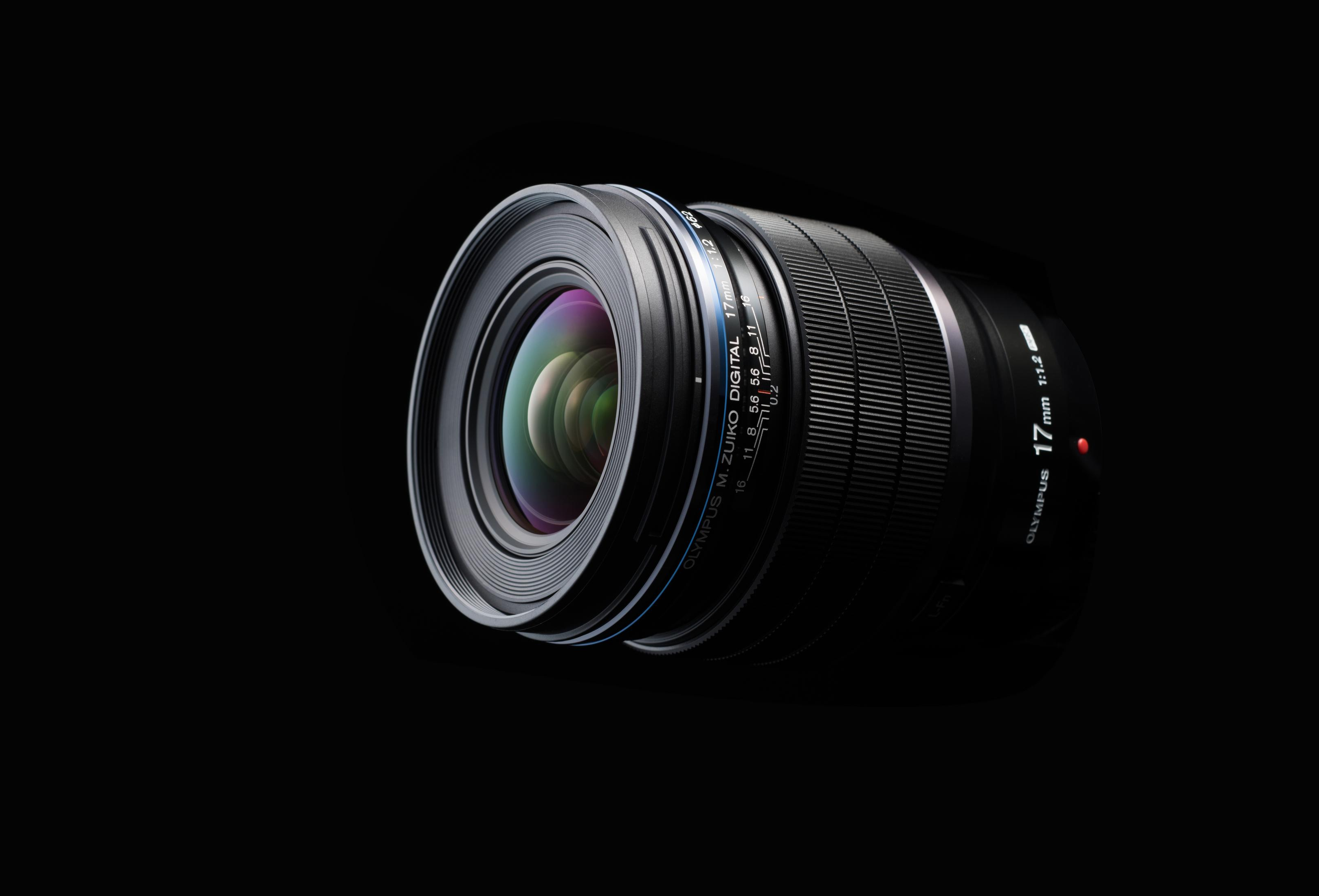 Ein Olympus M. Zuiko Digitalobjektiv. Es ist schwarz mit silbernen Details. Der Hintergrund ist schlicht schwarz.