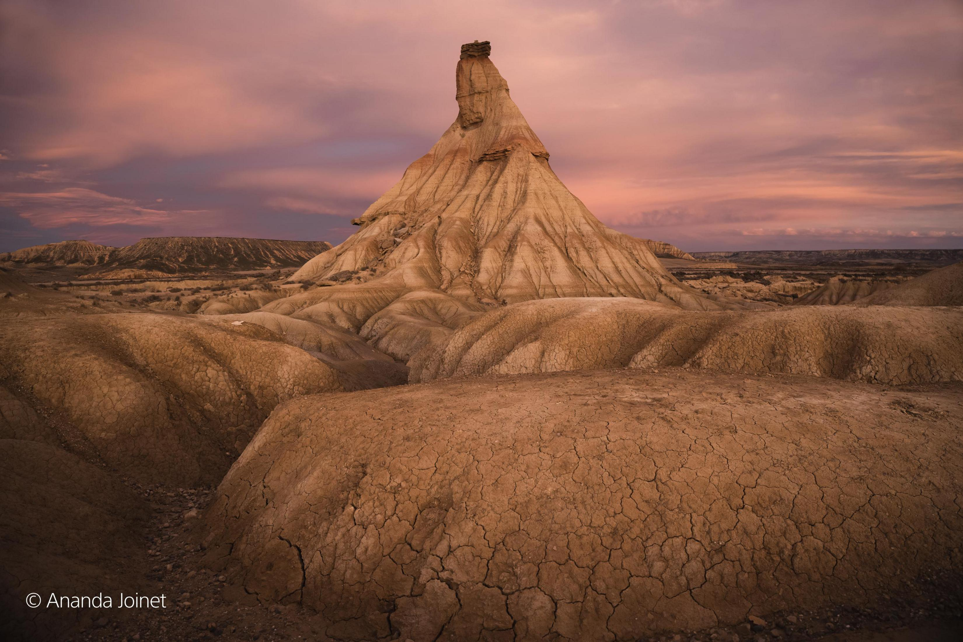 Motocyklista w stroju wyścigowym pochyla się w zakręcie na czerwono-zielonym motocyklu.