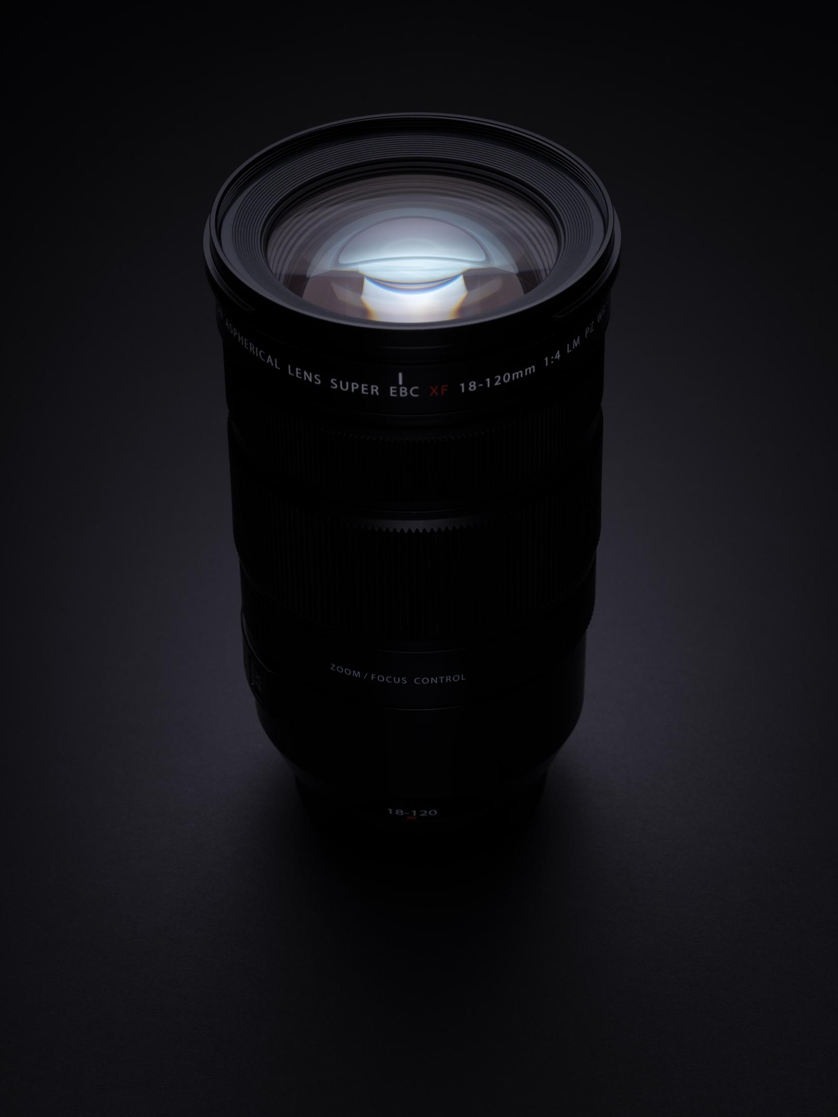 Czarny obiektyw aparatu z oznaczeniami. Ciemne tło. Obiektyw jest oświetlony od góry.