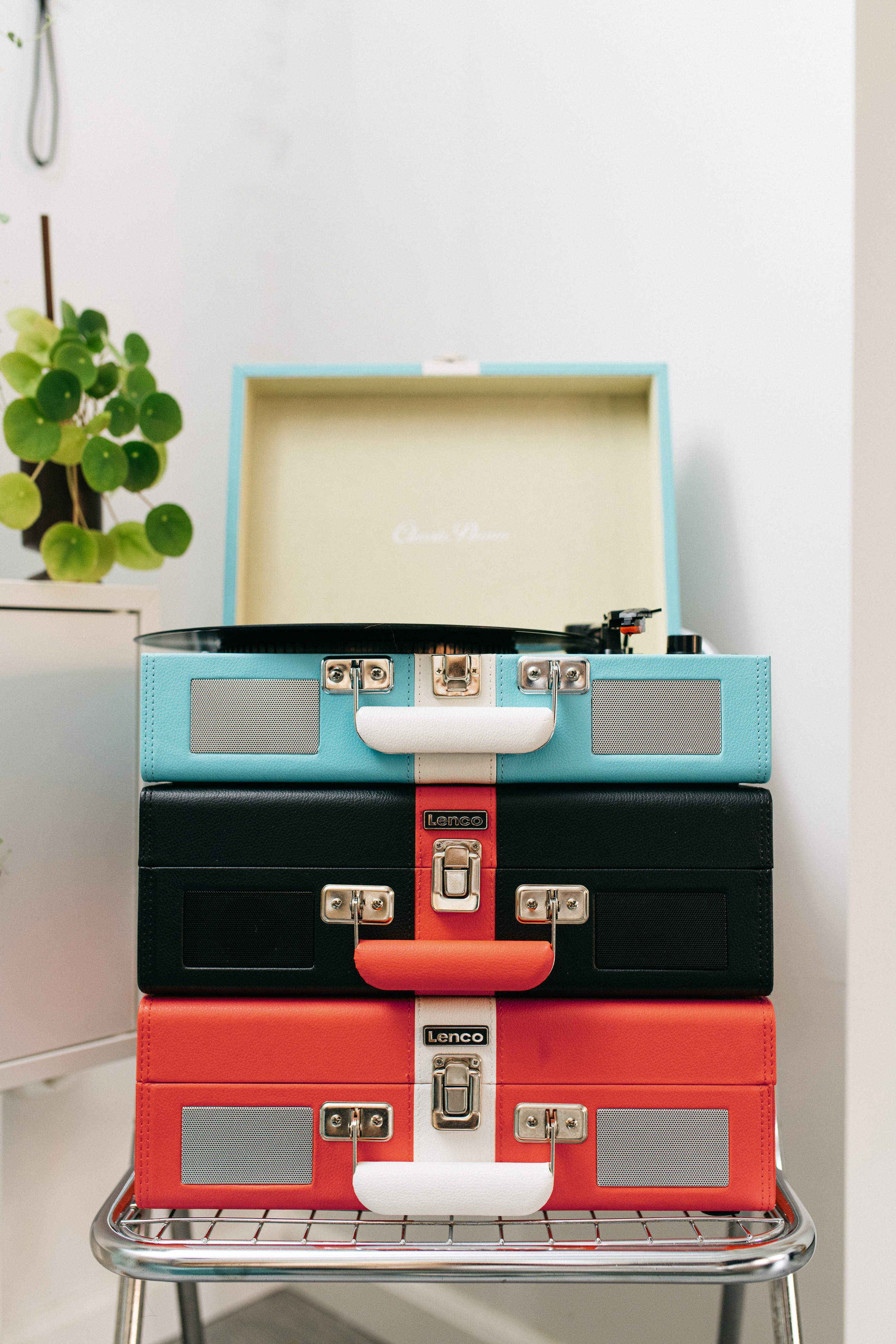 Trzy ułożone na sobie odtwarzacze płyt winylowych w kolorach: niebieskim, czarnym i czerwonym.