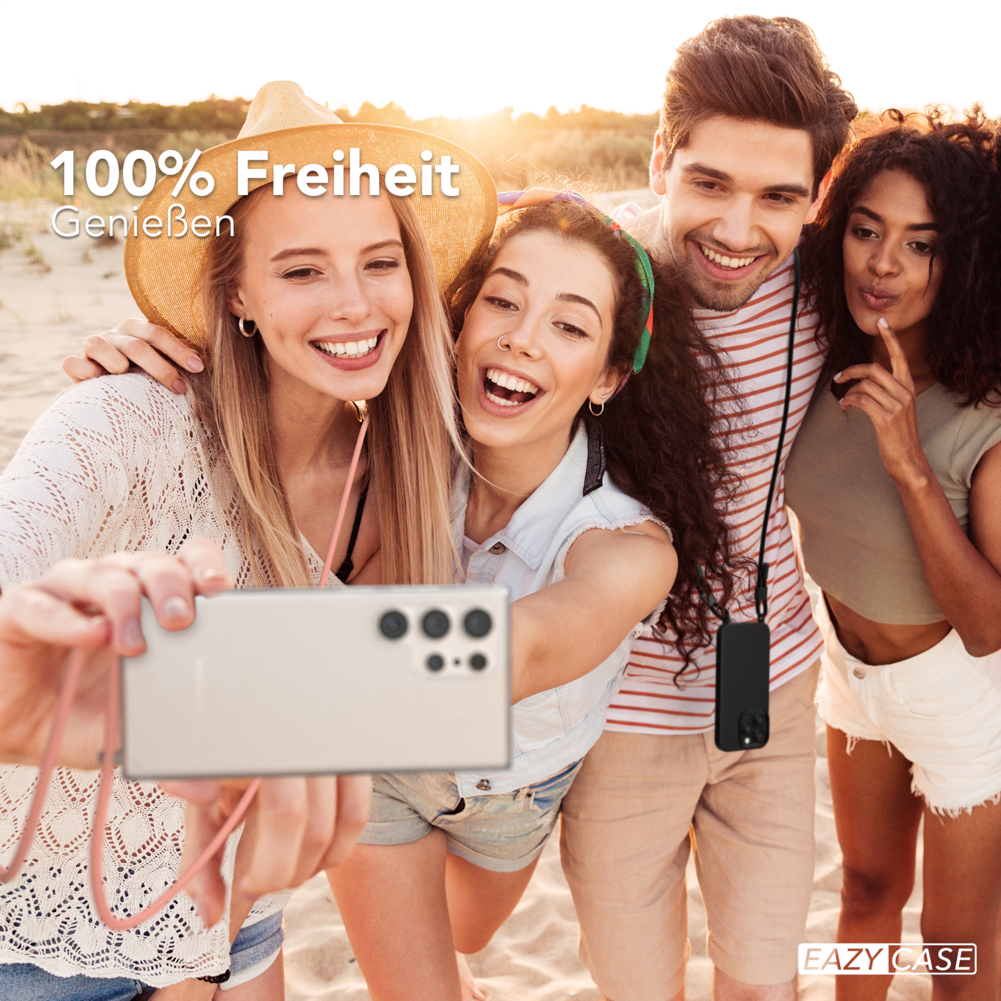 Vier Personen machen Selfie am Strand, lächeln, halten Telefon.