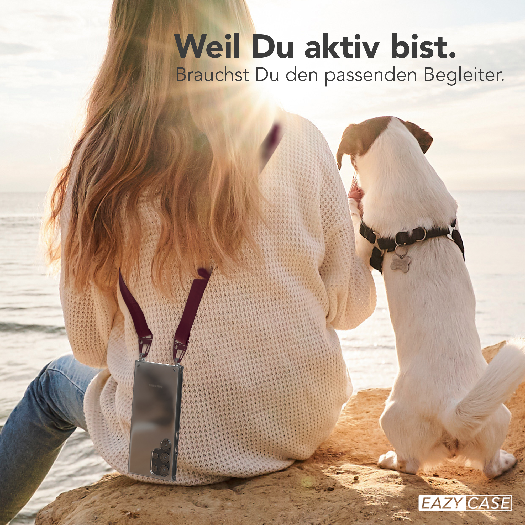 Frau mit Handyhülle und Hund am Strand. Sonne im Hintergrund. Produktwerbung.