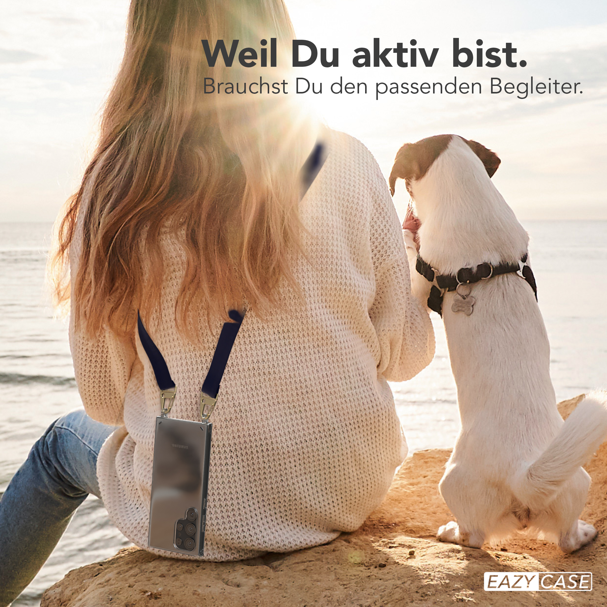 Frau mit Telefon an Lanyard sitzt auf Felsen, Hund in der Nähe.