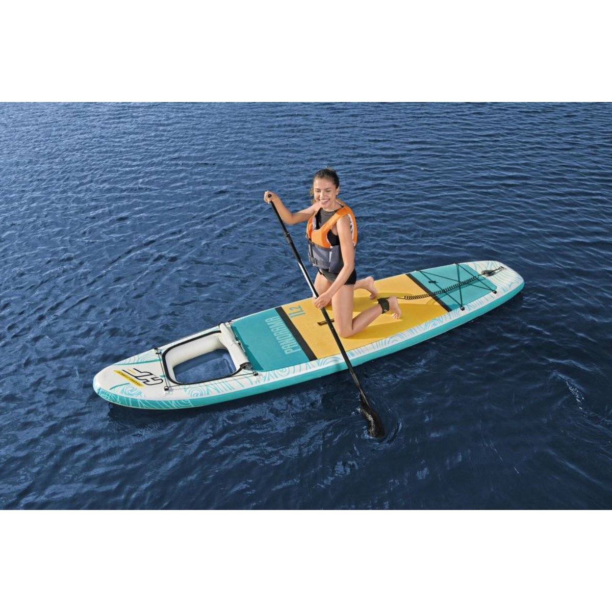 Vrouw knielend op een blauw-wit paddleboard op water, met een peddel.