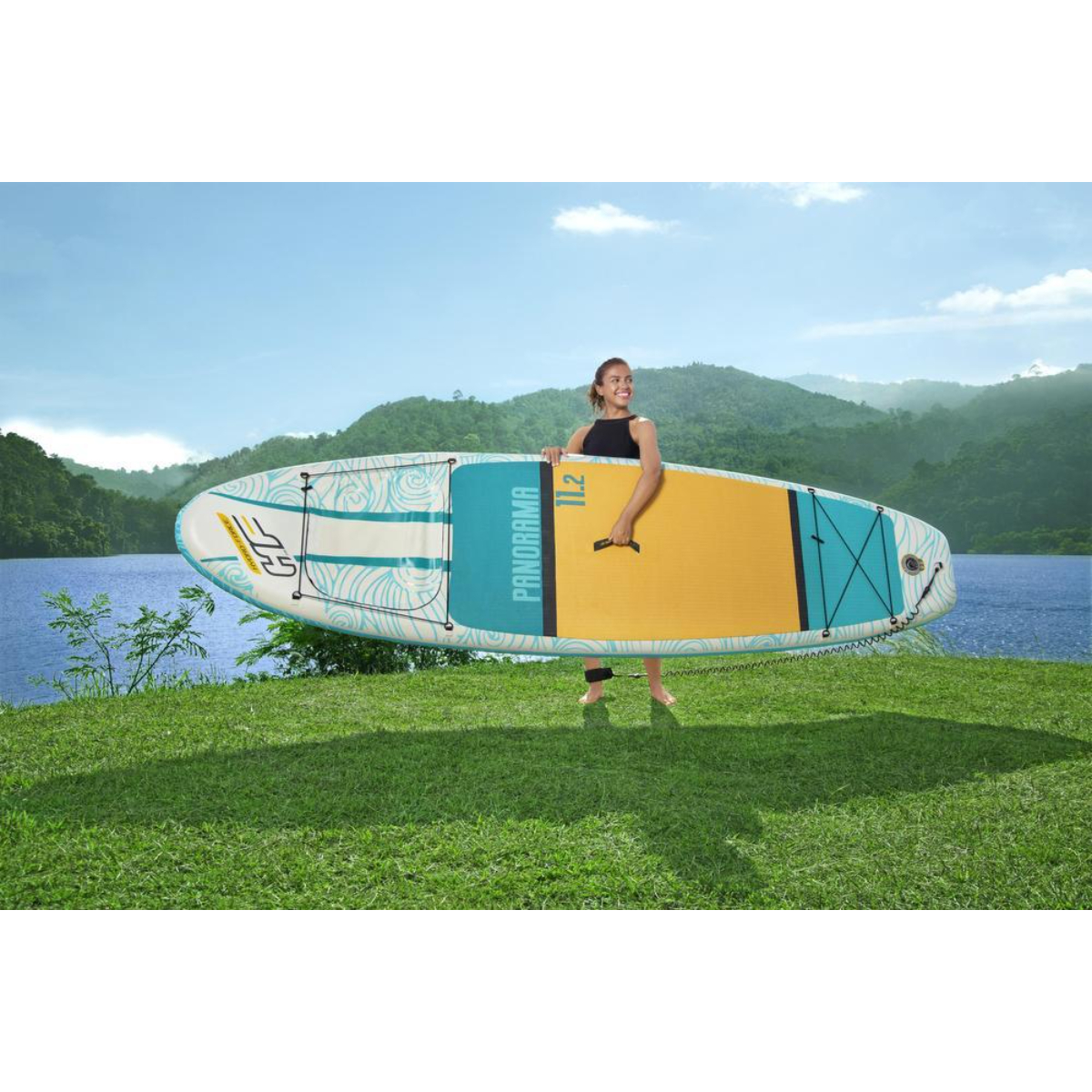 Vrouw op een paddleboard op een meer. Blauw water en lucht. Groene gras oever met bomen.