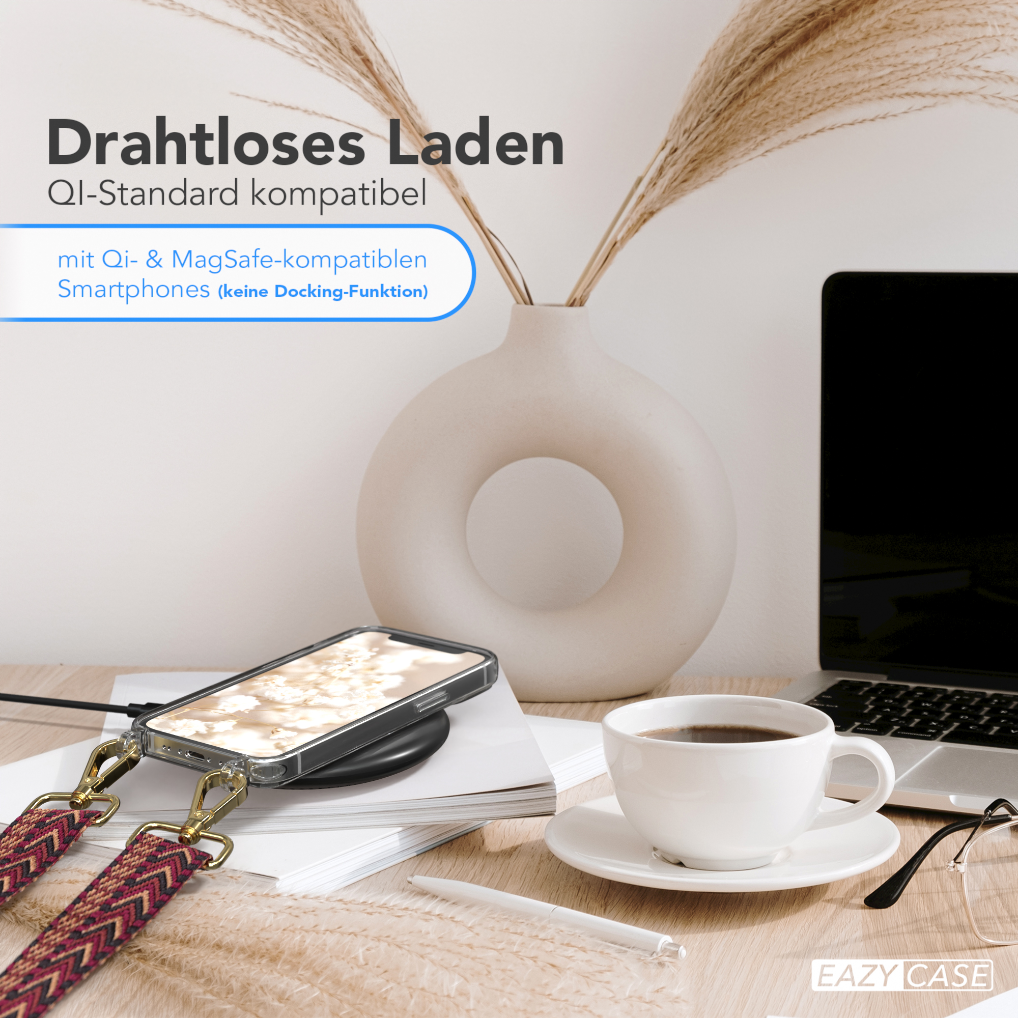 Telefon in Hülle auf Ladepad, mit Kaffee, Blumen und Laptop im Hintergrund.