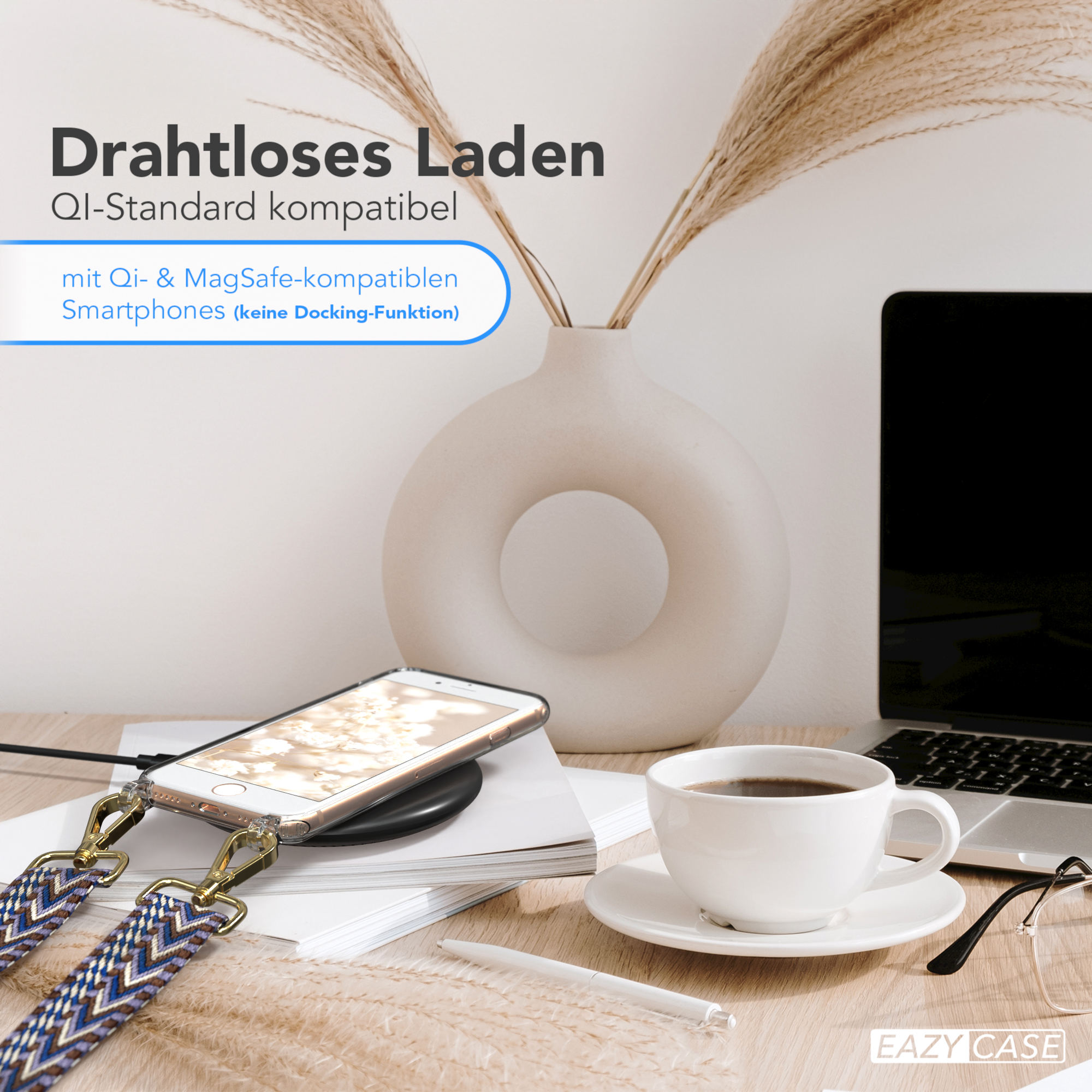 Ein Smartphone auf einem kabellosen Ladegerät mit Handytaschenband und eine Kaffeetasse auf einem Schreibtisch.
