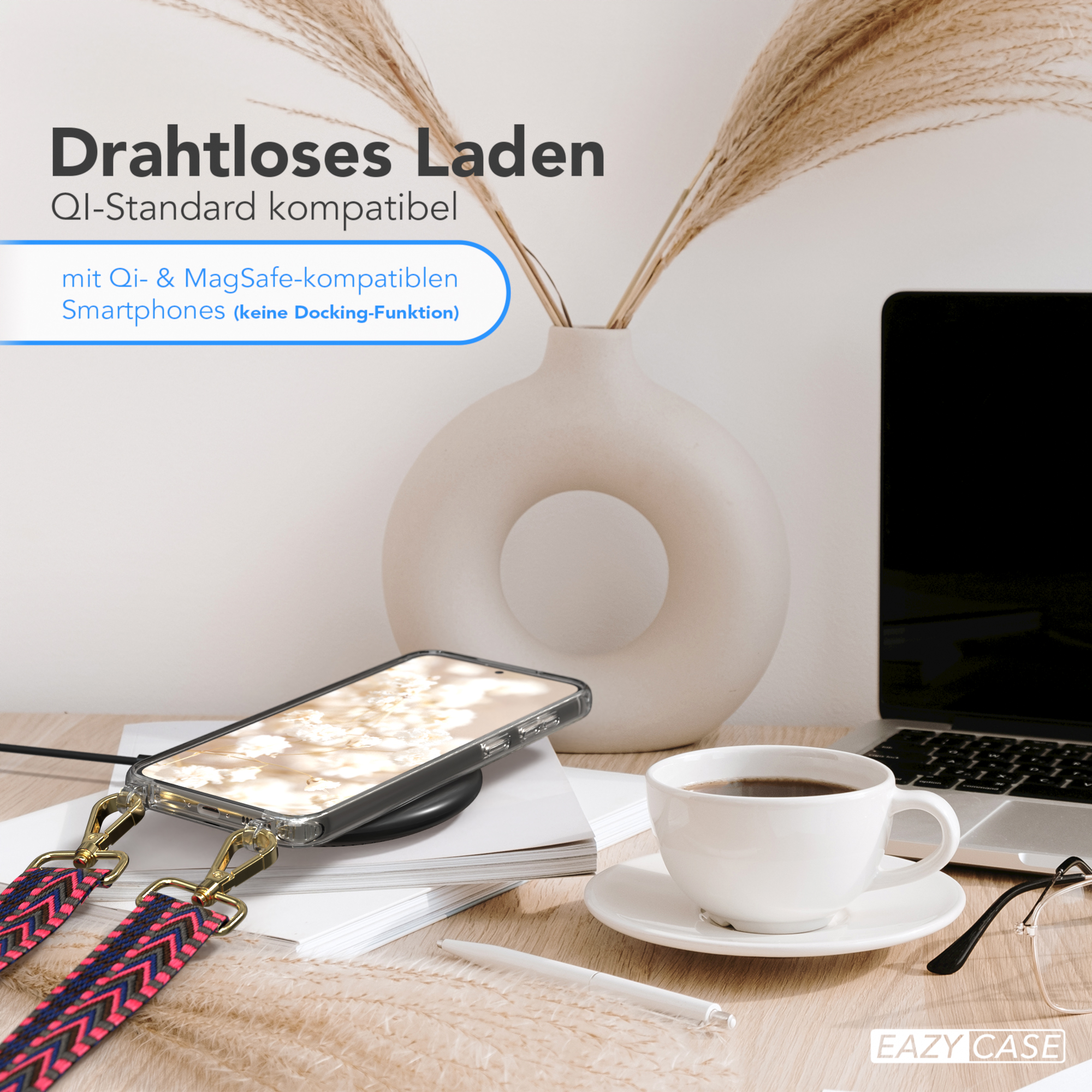 Ein Telefon auf einem kabellosen Ladegerät, neben einer Kaffeetasse, Blumen in einer Vase und einem Laptop.