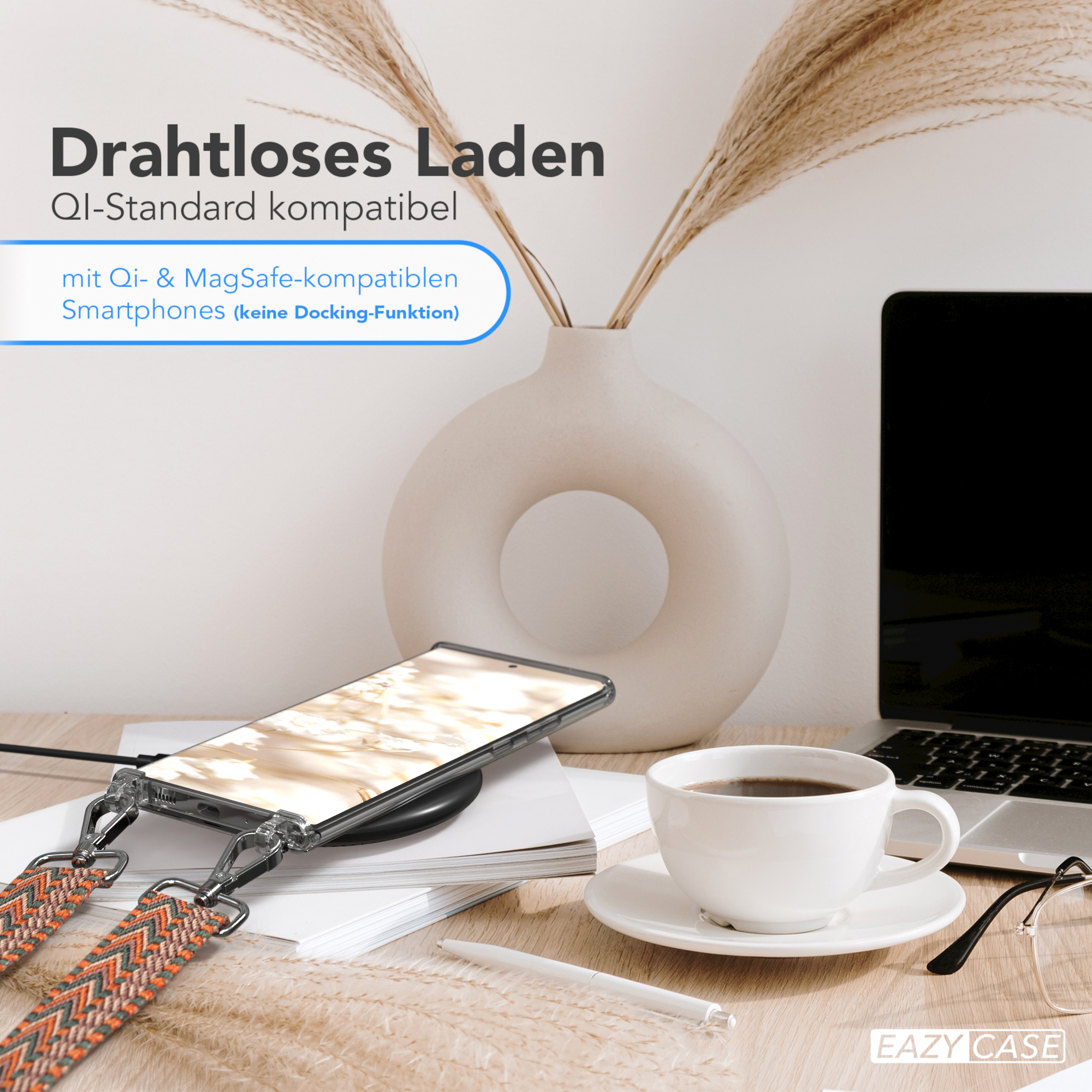 Ein Telefon auf einem kabellosen Ladegerät, eine Kaffeetasse und dekorative Stiele liegen auf einem Holztisch.