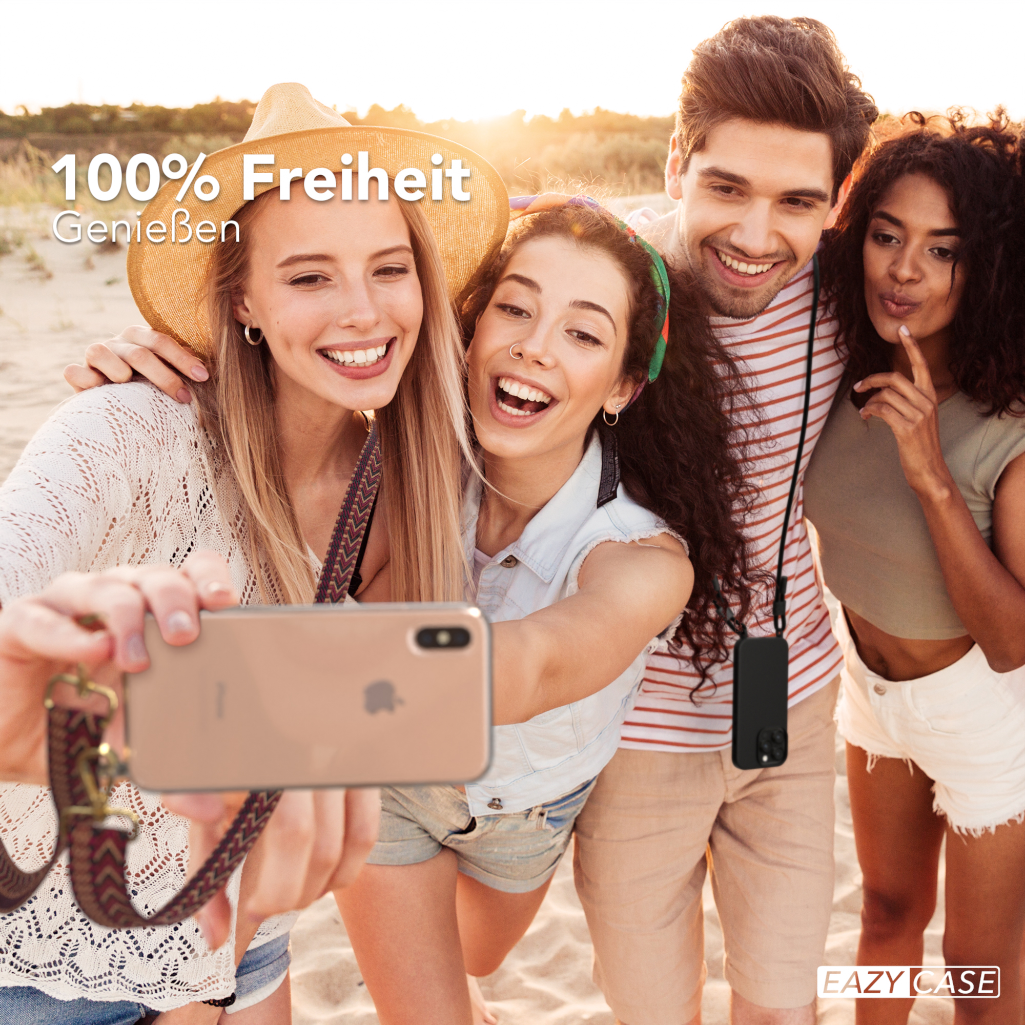 Vier Personen machen ein Selfie am Strand. Einer hält das Telefon. Klarer Himmel.