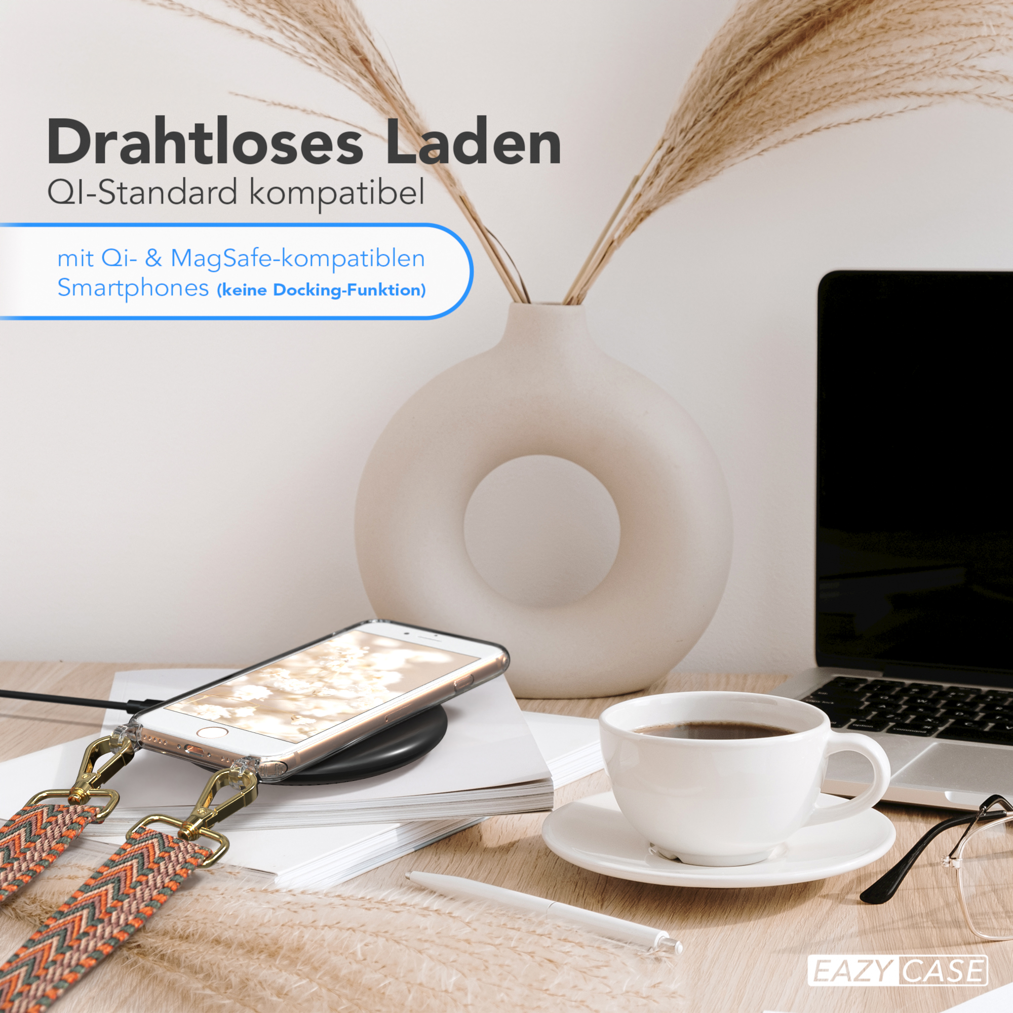 Ein Telefon auf einem Ladepad, eine Kaffeetasse und ein Laptop auf einem Schreibtisch mit einer Vase.