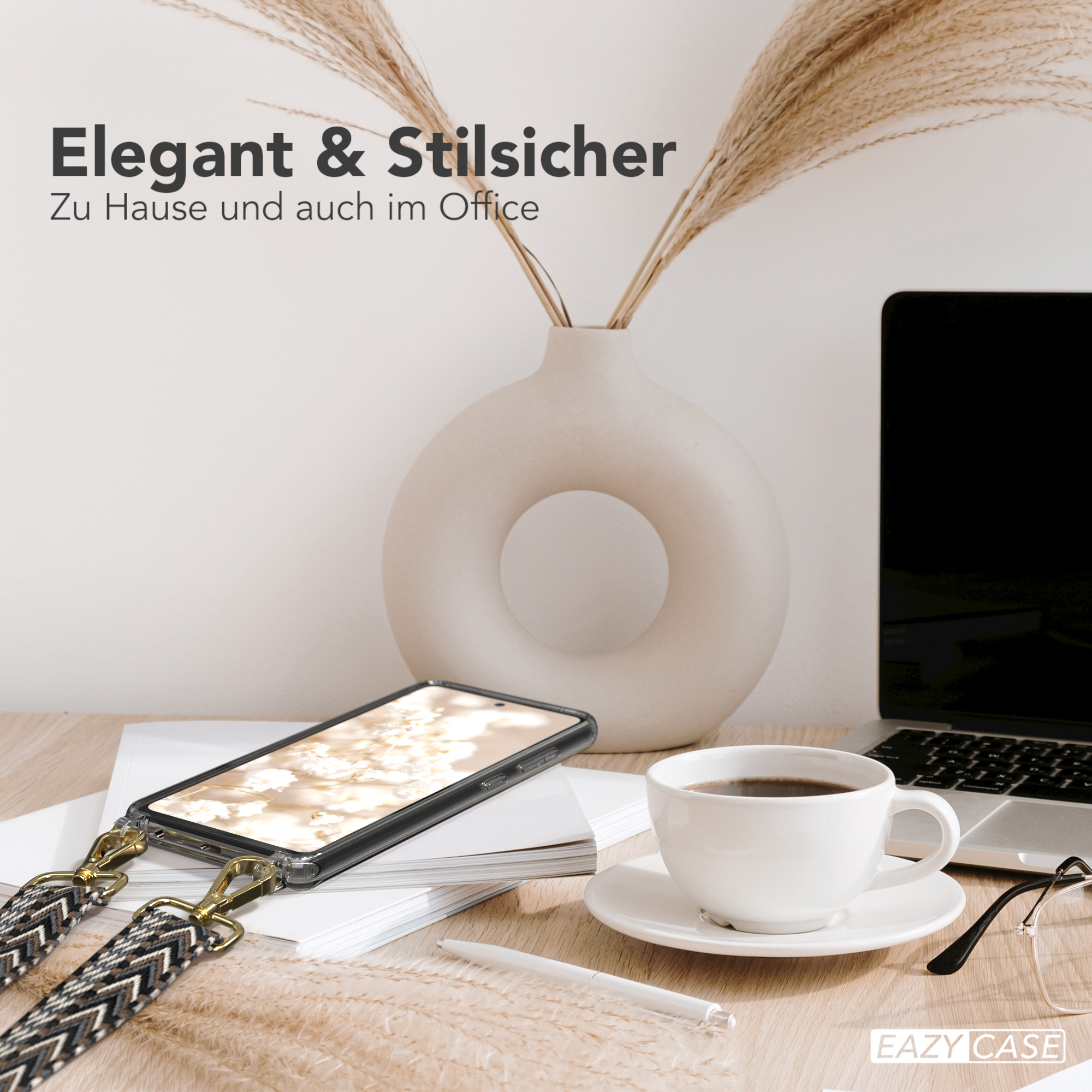 Ein Telefon mit Lanyard auf einem Schreibtisch, mit Kaffee, Brille und Vase.