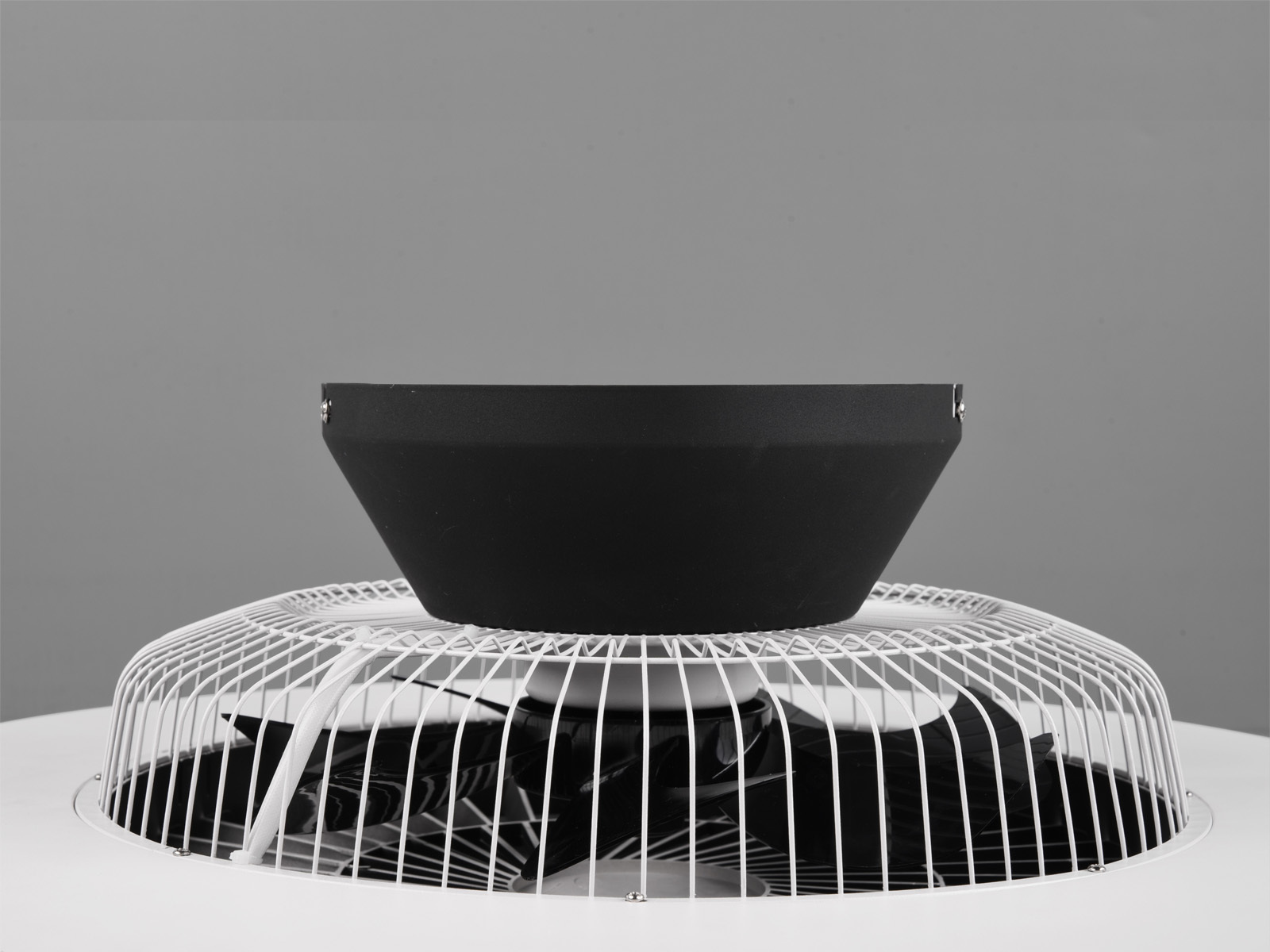 Un ventilador de techo con aspas blancas, centro negro y fondo blanco.