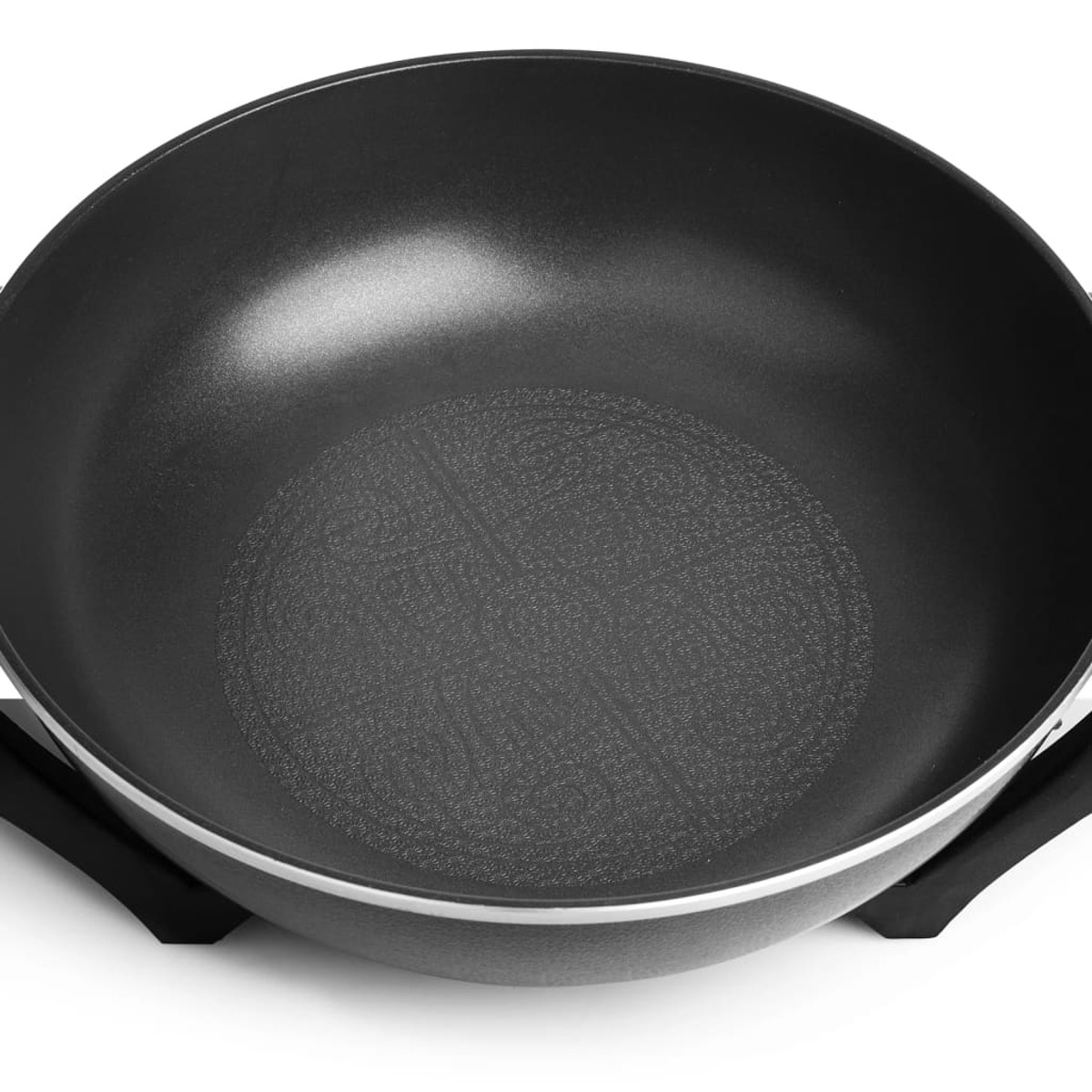 Una sartén wok negra con interior texturizado, tomada desde arriba sobre una superficie blanca.