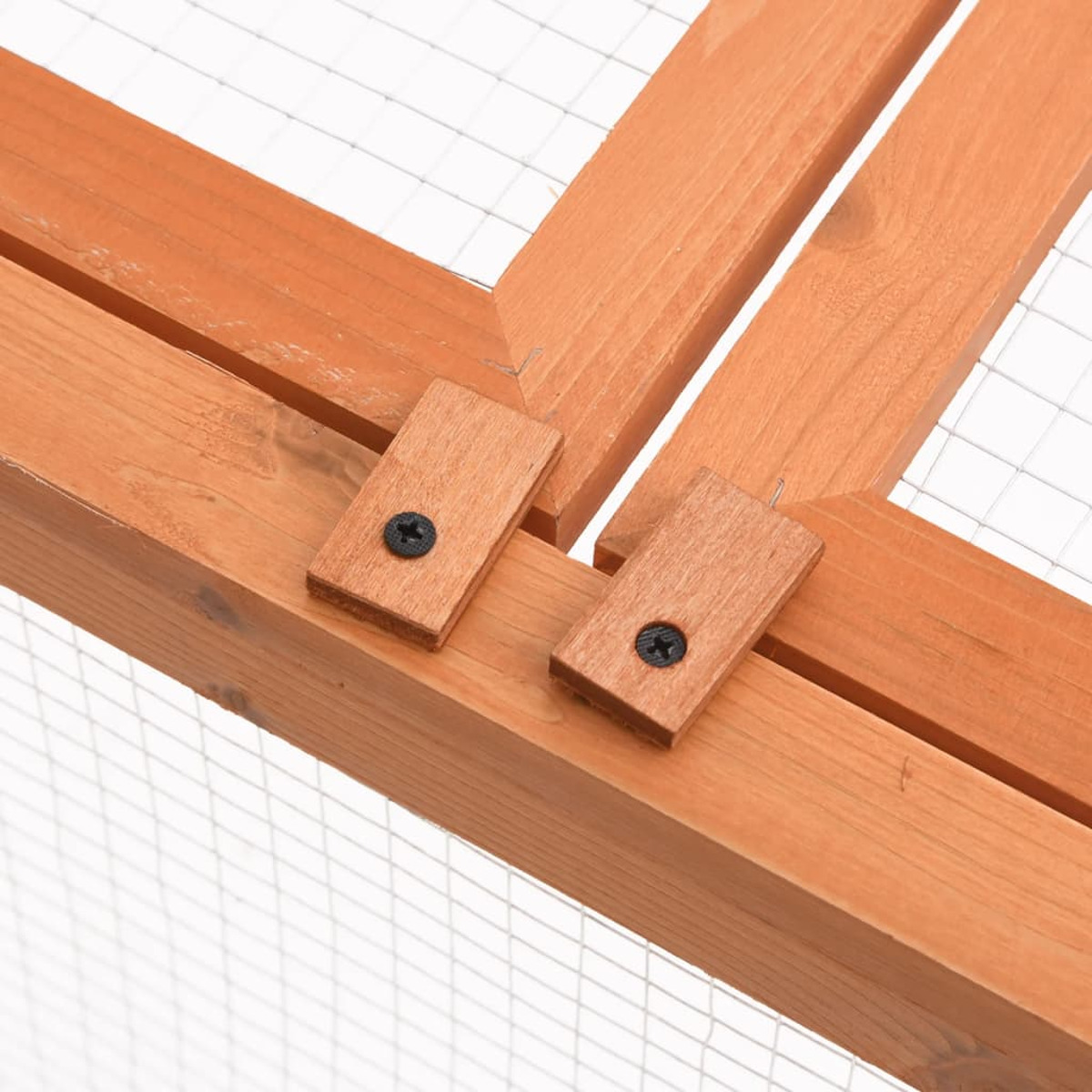 Holzrahmenecke mit Metallgitter. Zwei kleine Holzstücke mit Schrauben sichern den Rahmen.