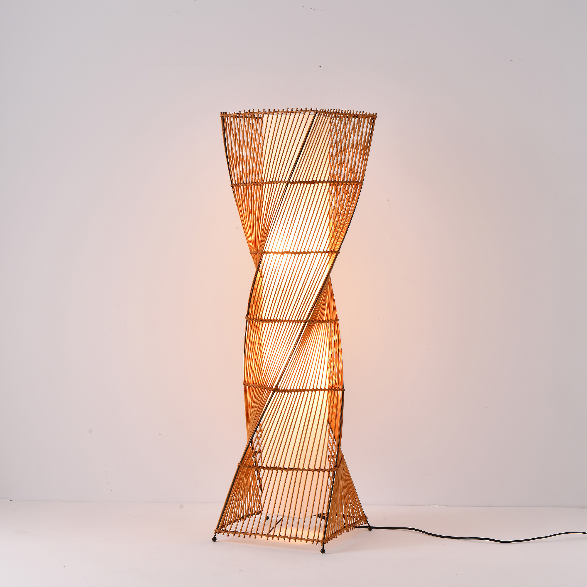 Spiral-förmige Bambus-Stehlampe auf weißem Hintergrund.